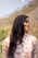 A woman with long hair standing in front of a mountain