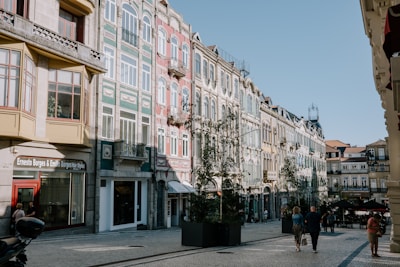 A group of people walking down a street next to tall buildings