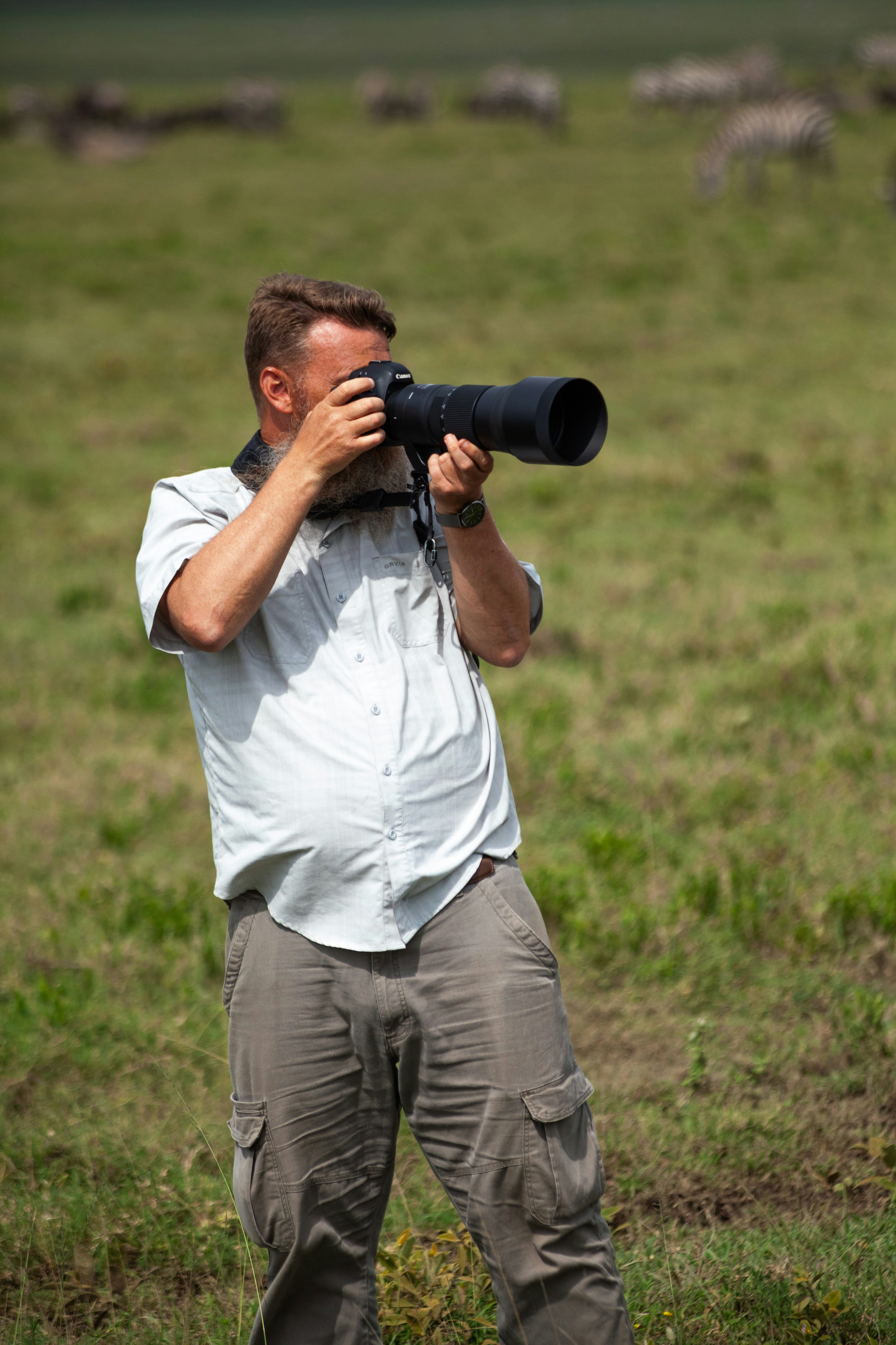 A man standing in a field taking a picture with a camera photo – Free ...