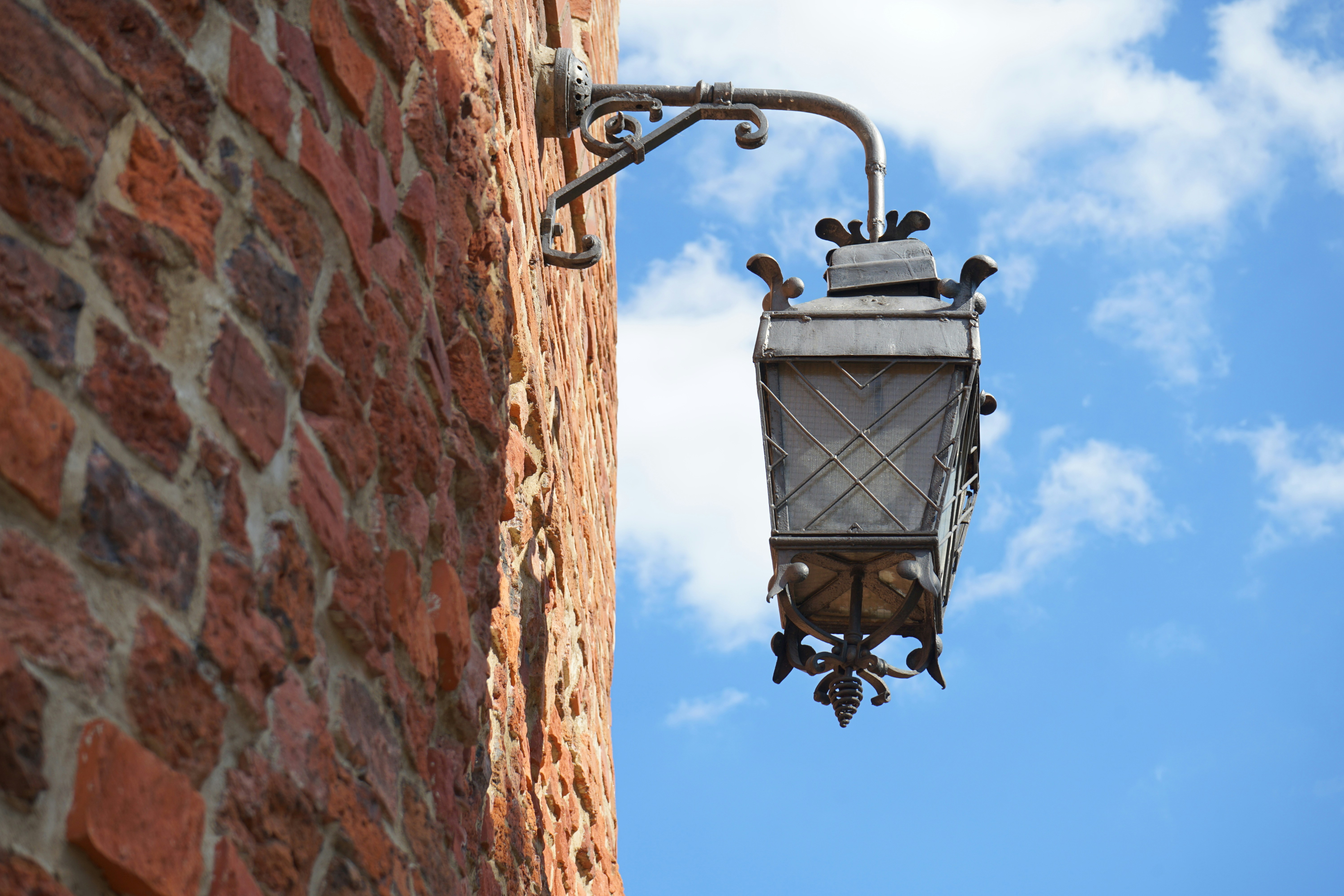 A street light hanging from the side of a brick building photo – Free ...