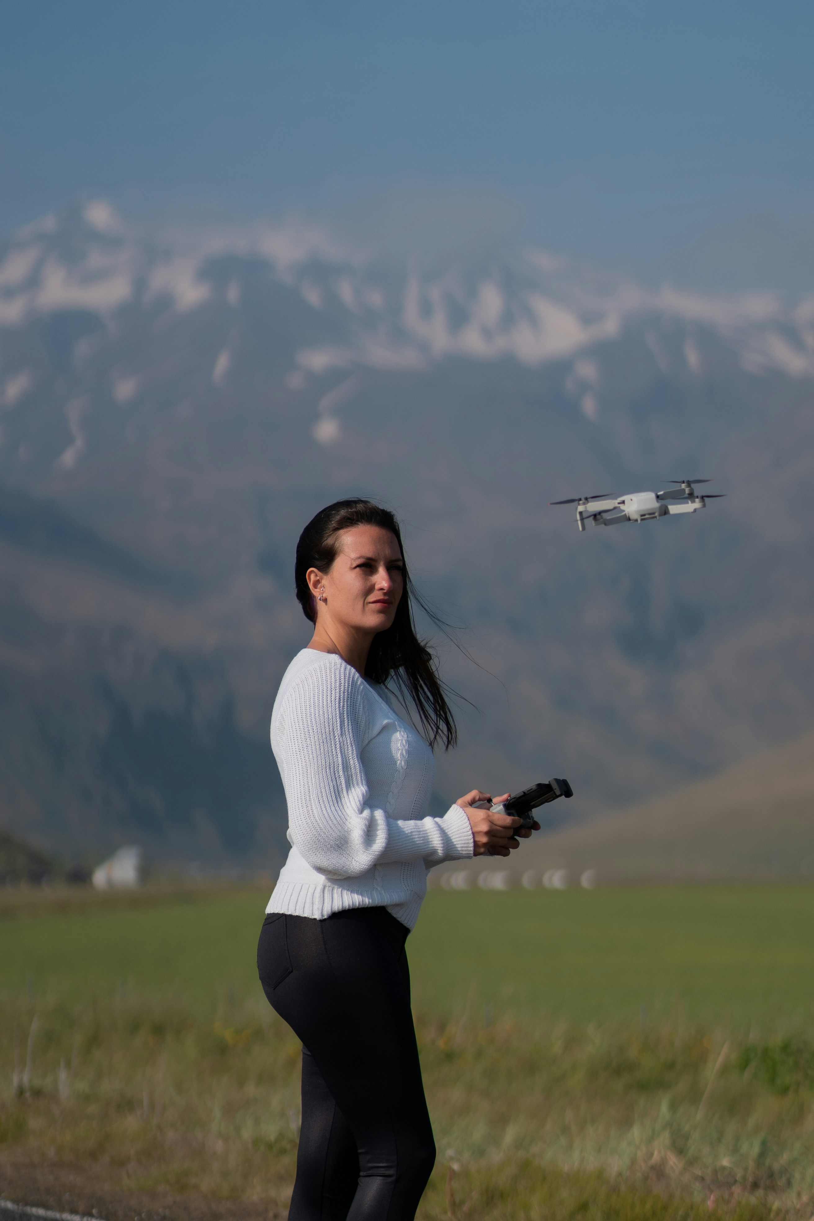 A woman standing on the side of a road with a remote control plane in the