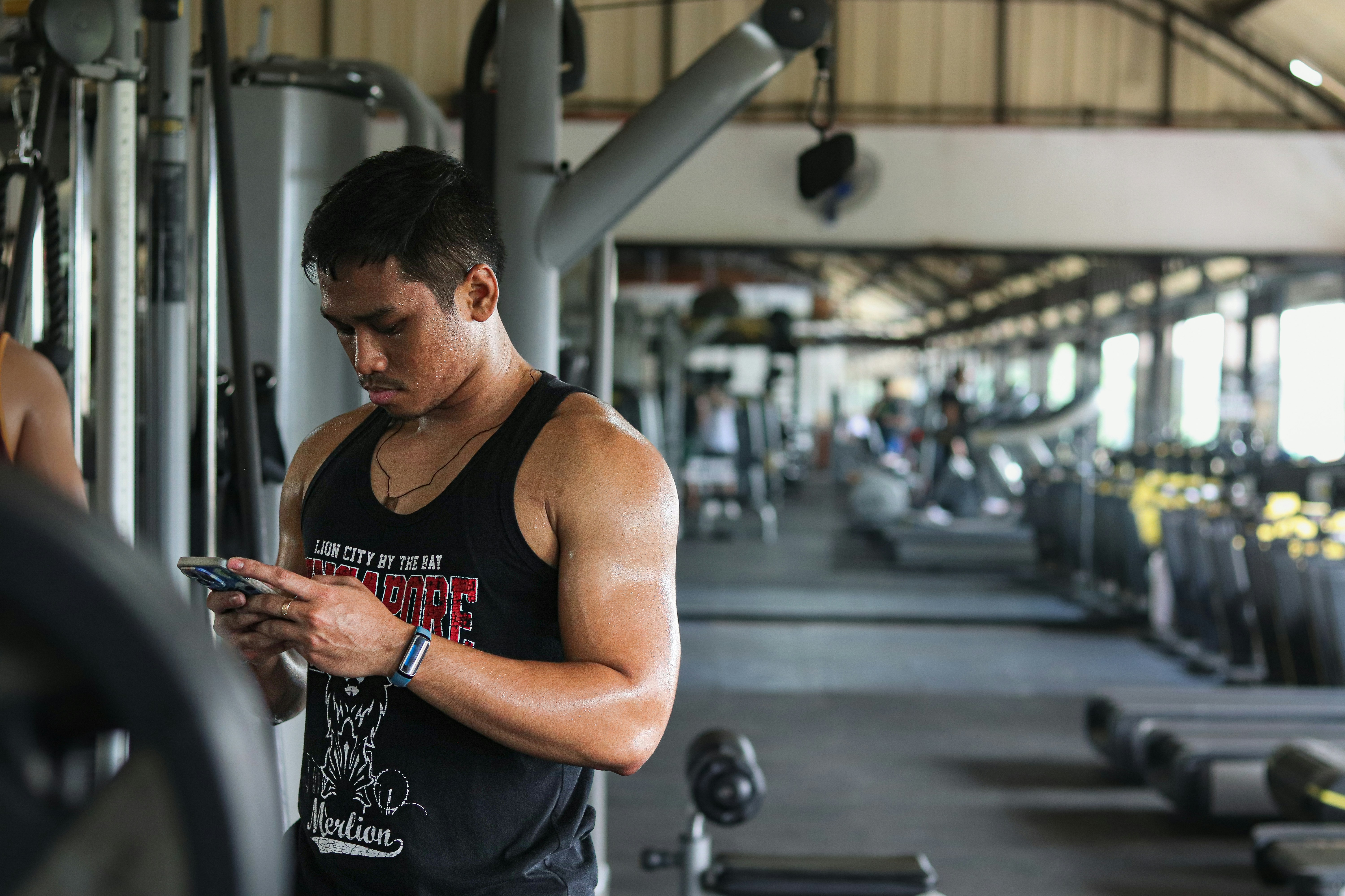 A man in a gym looking at his cell phone