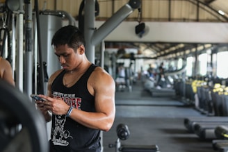 A man in a gym looking at his cell phone