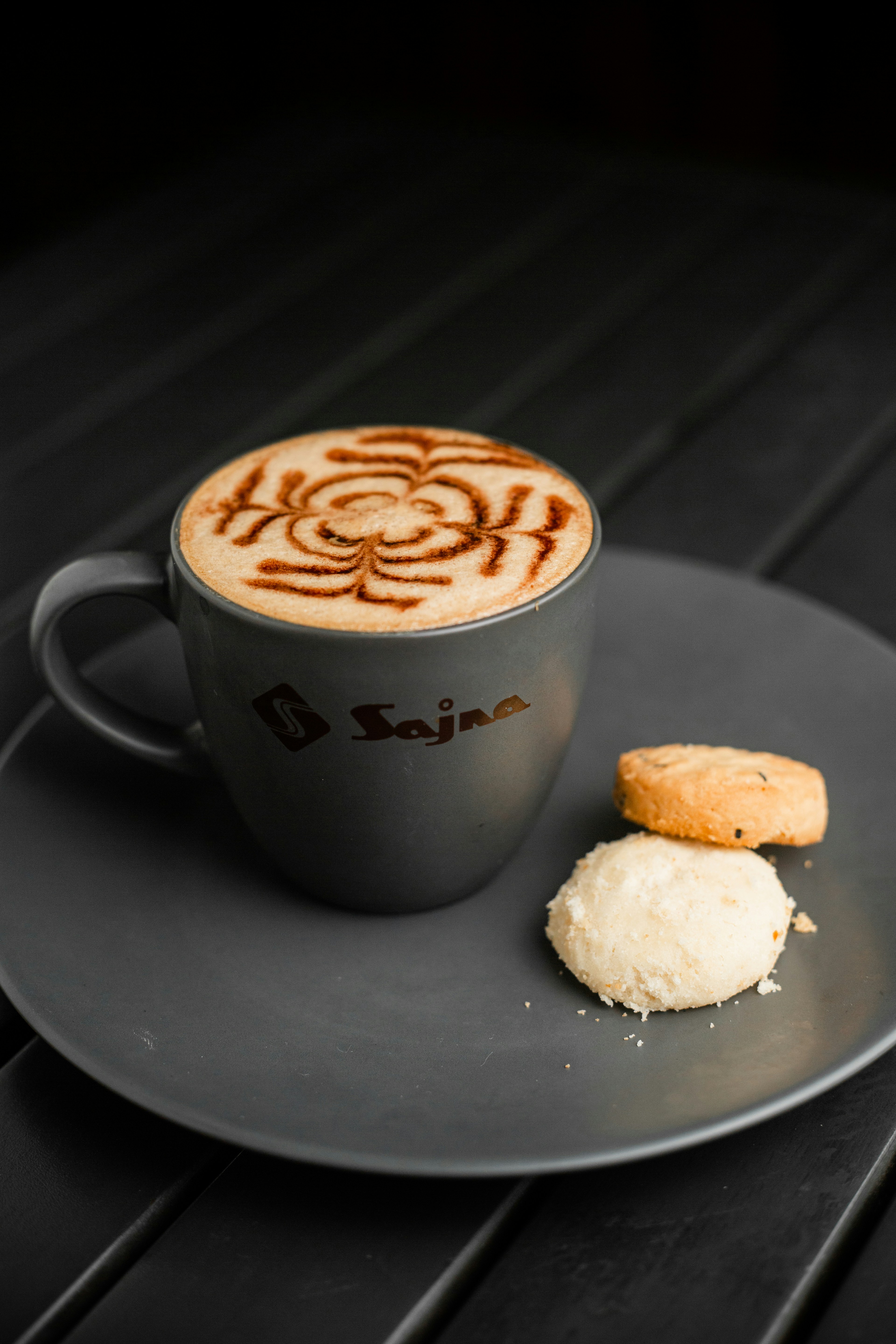 A cup of coffee and a biscuit on a plate