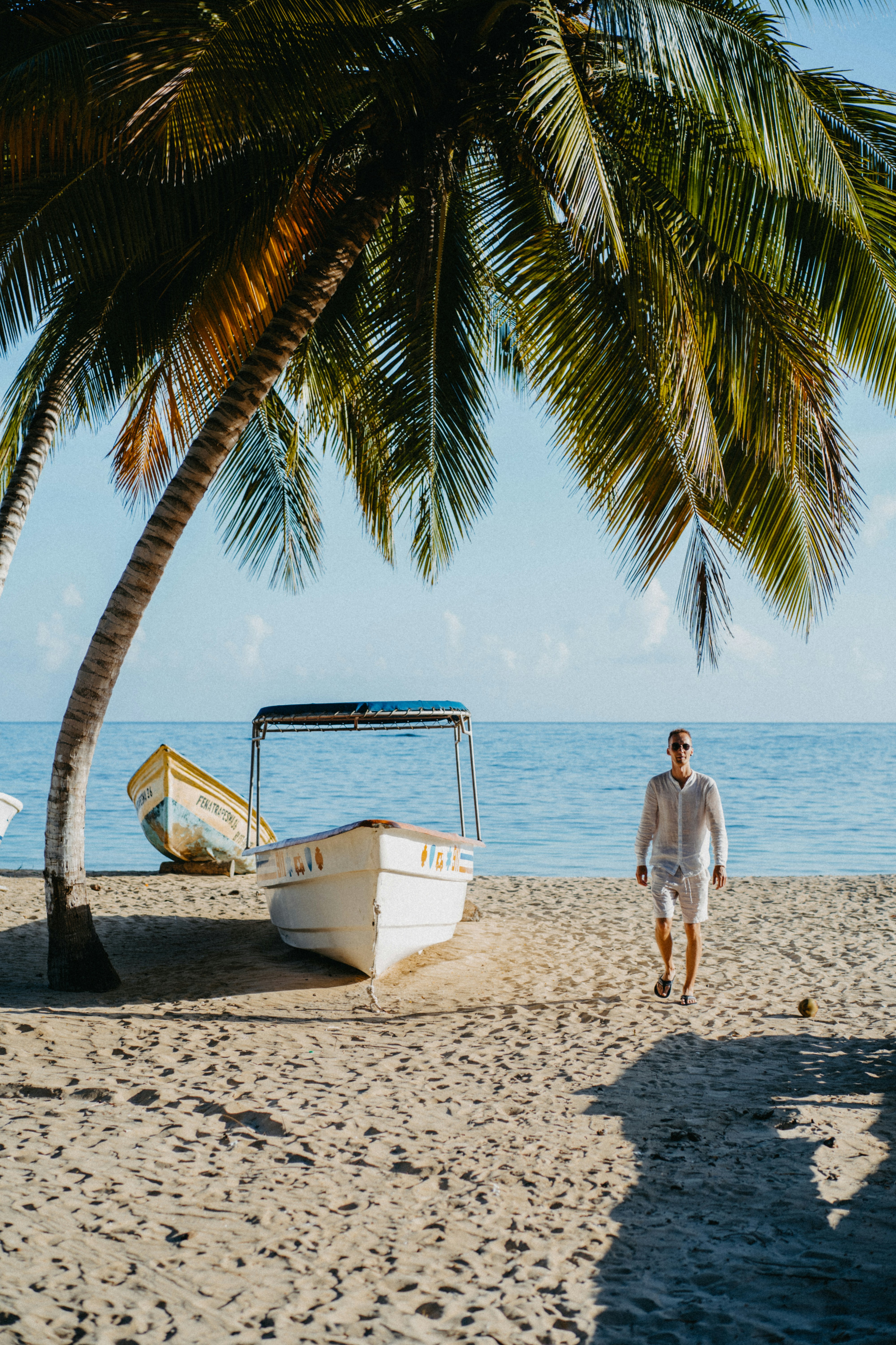 A man standing on a beach next to a boat