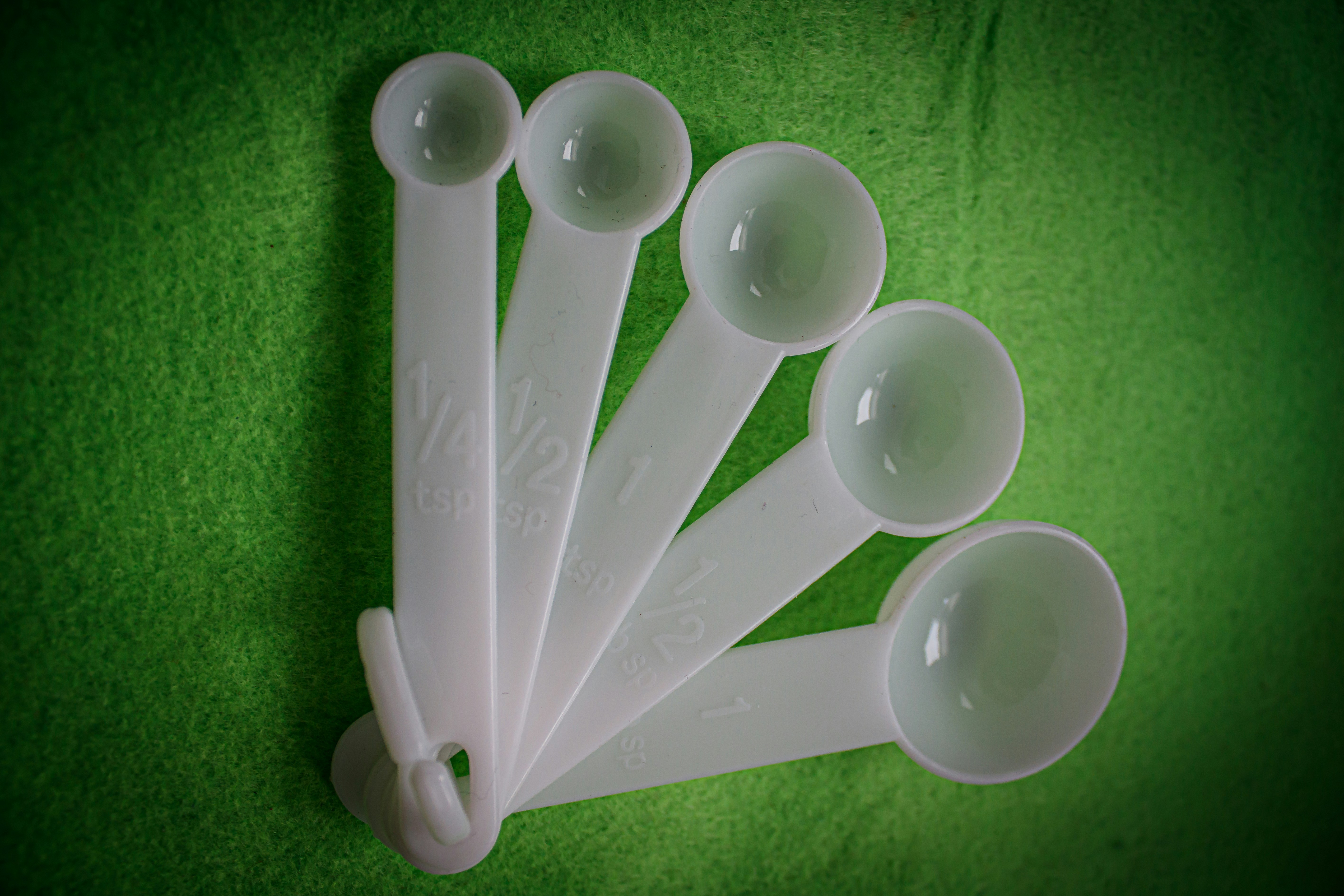 A group of plastic spoons sitting on top of a green surface