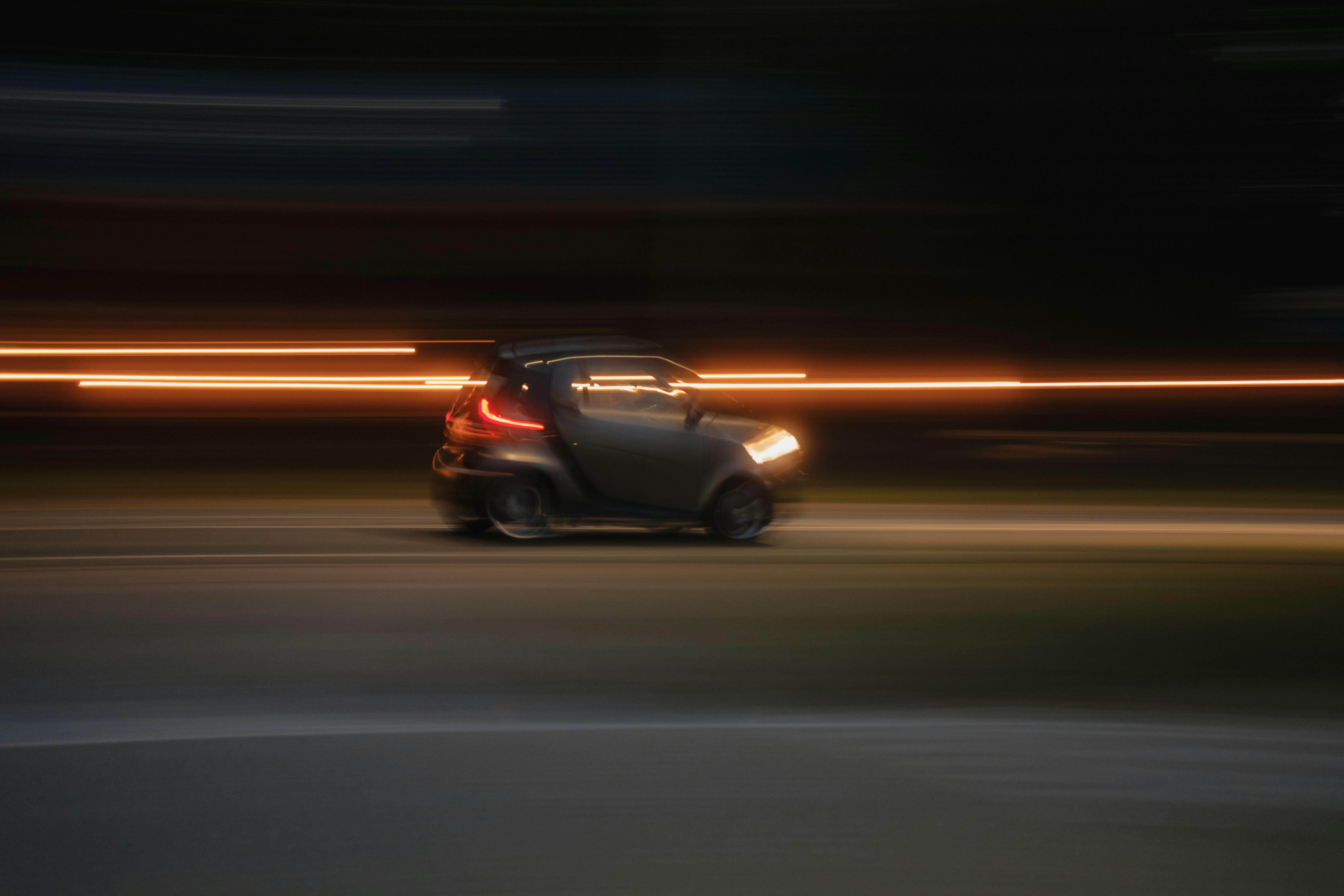 A small car driving down a street at night