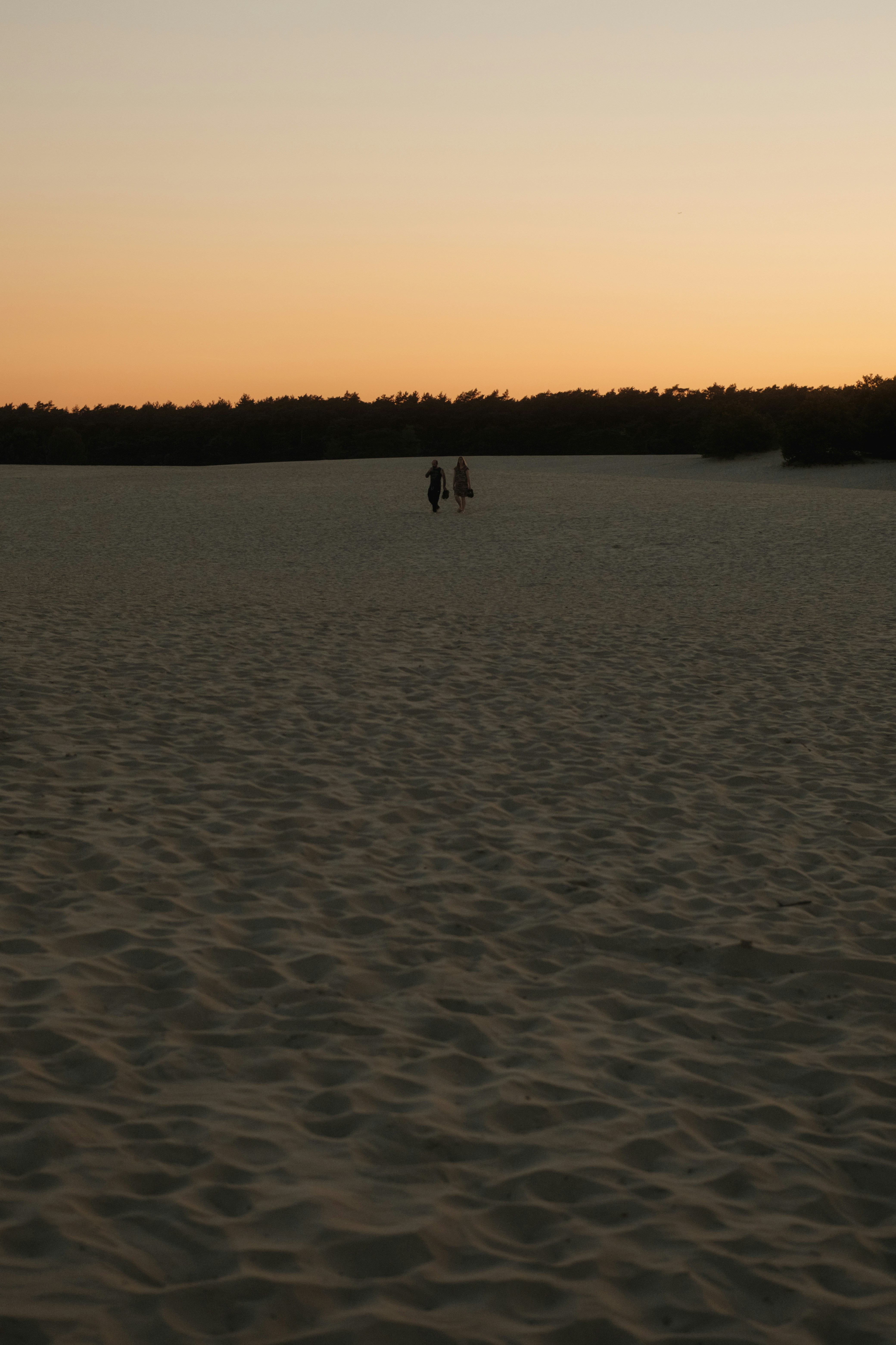 A couple of people standing on top of a sandy beach
