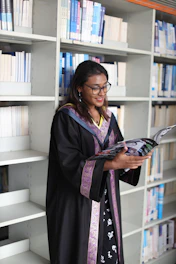 A woman in a graduation gown reading a book
