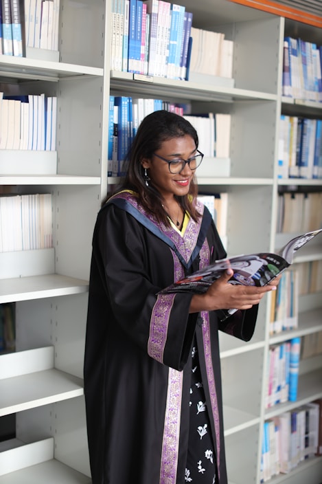 A woman in a graduation gown reading a book
