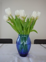 A blue vase filled with white flowers on top of a table