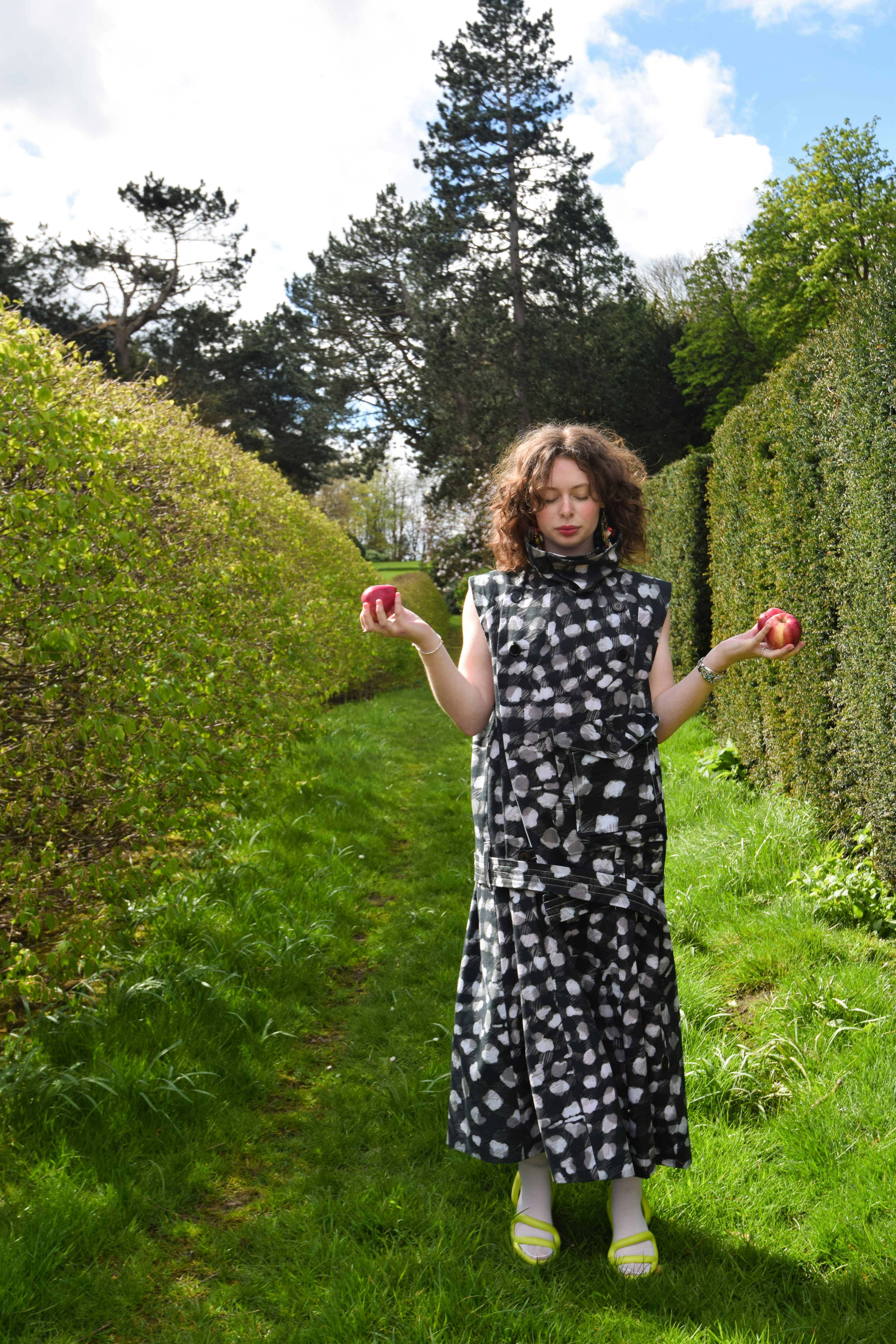 A woman in a black and white dress holding apples