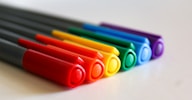 A row of colored pencils sitting on top of a white table