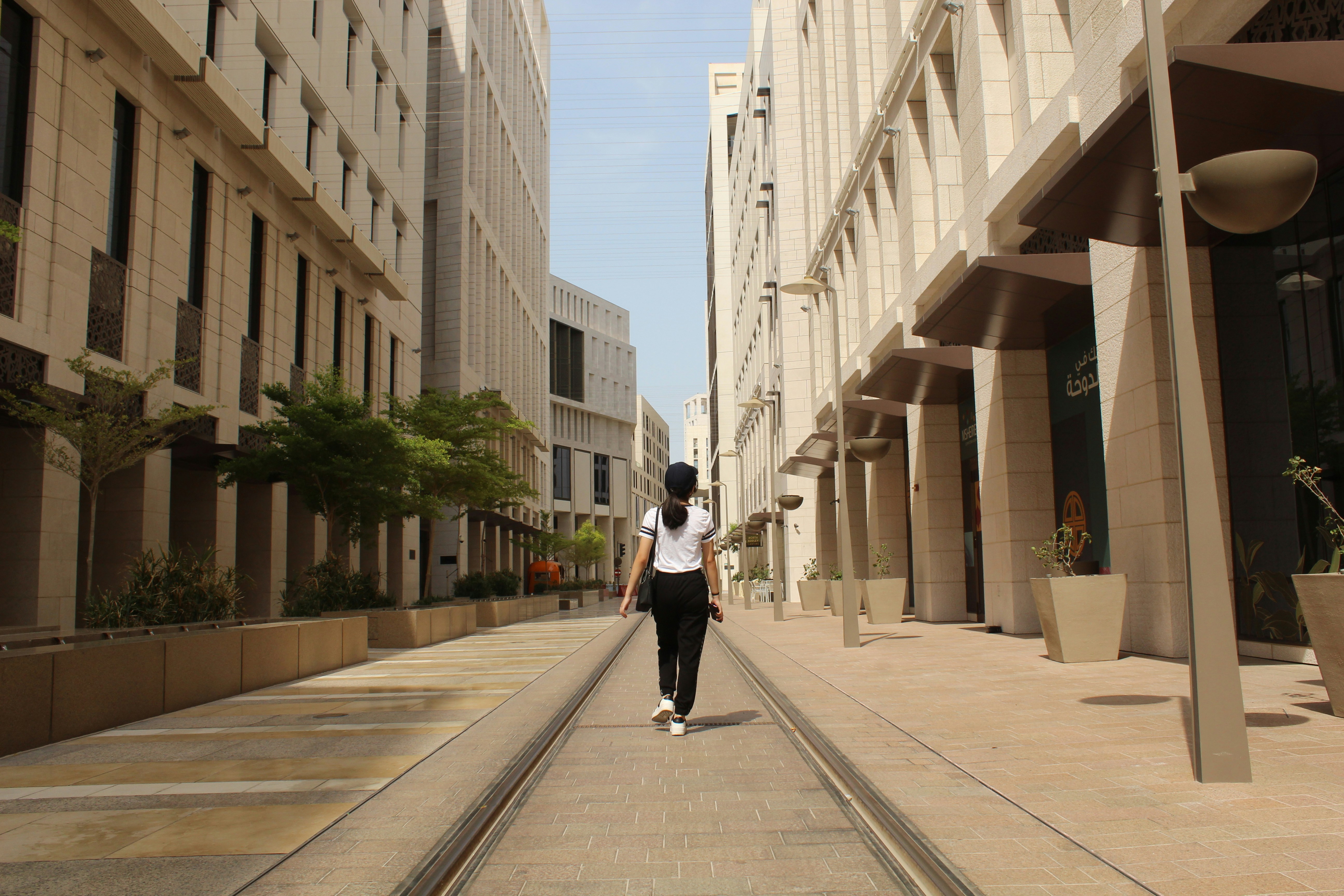A man walking down a street next to tall buildings