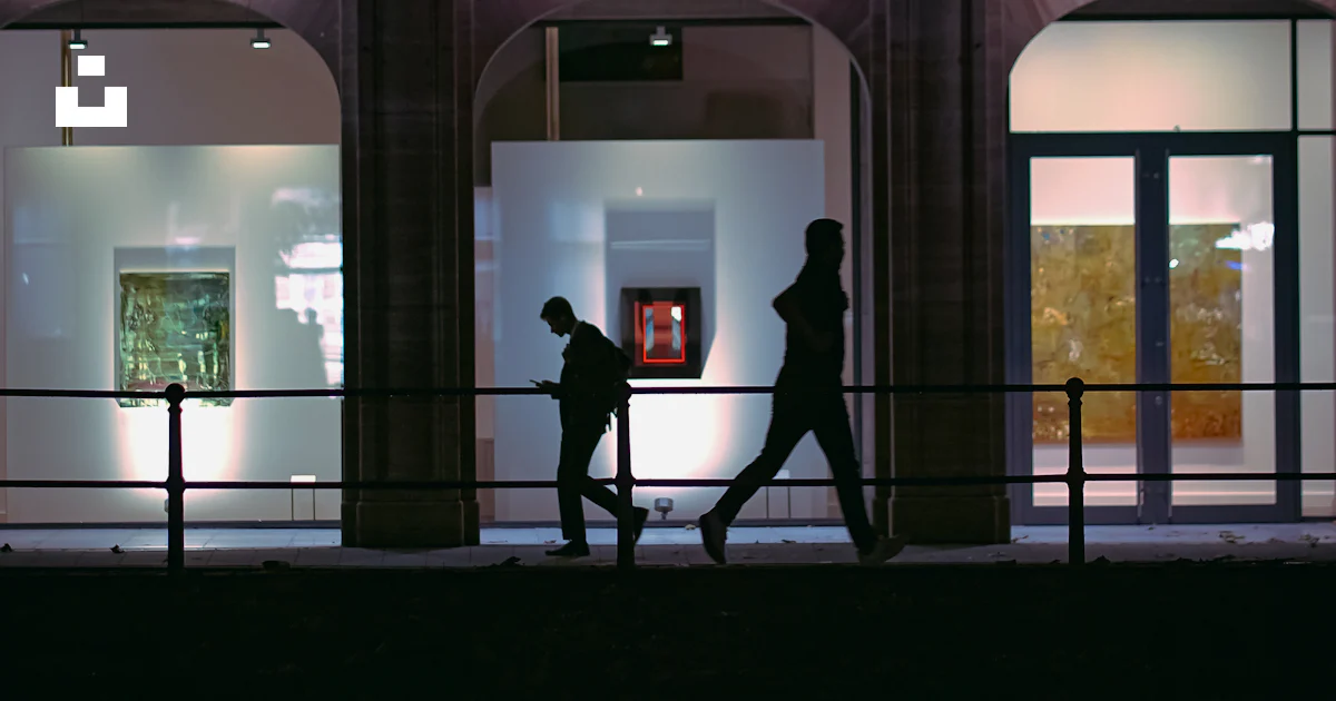 A couple of people walking past a tall building photo – Free Woman ...