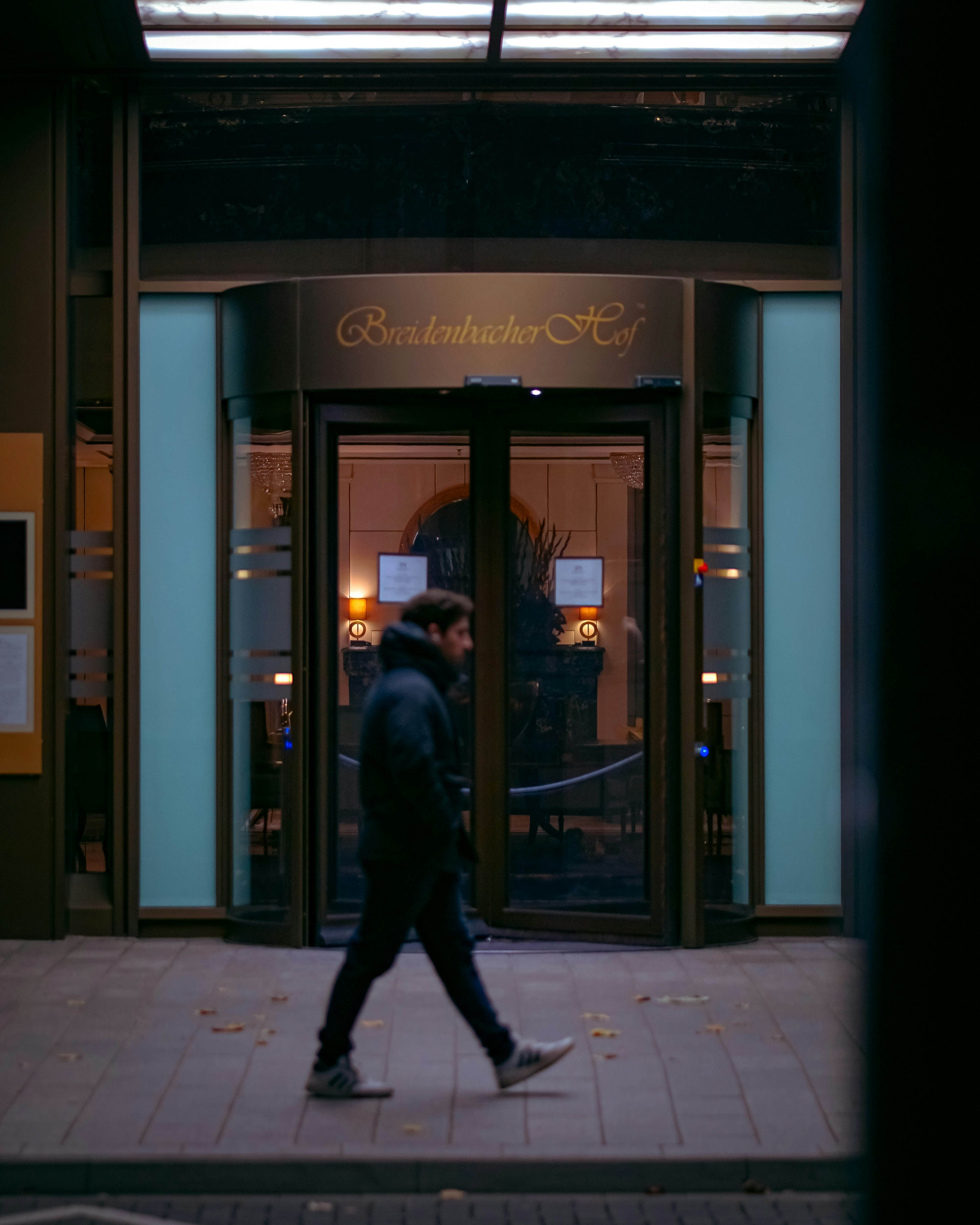 A man walking down a sidewalk in front of a building photo – Free Green ...