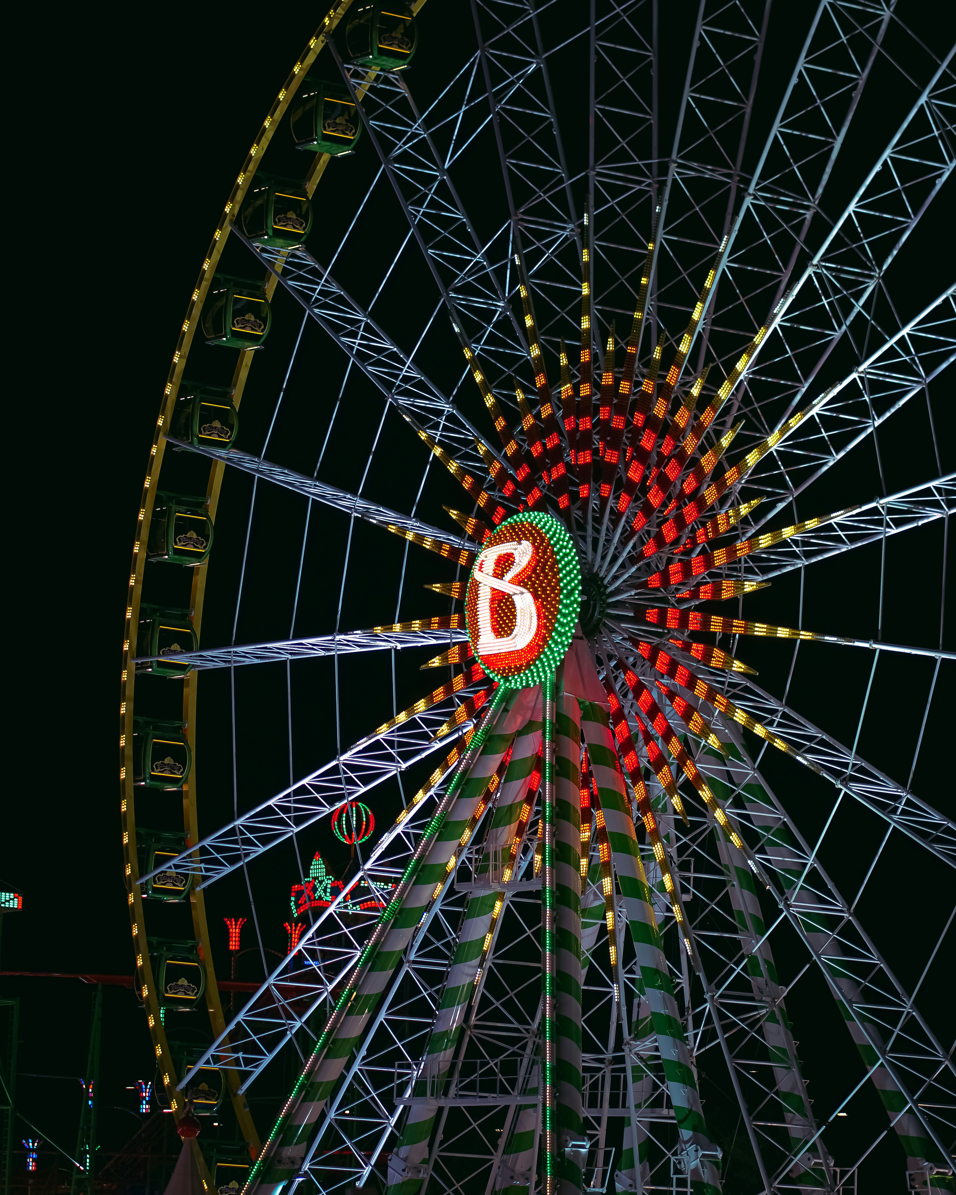 A ferris wheel lit up at night with the letter b on it