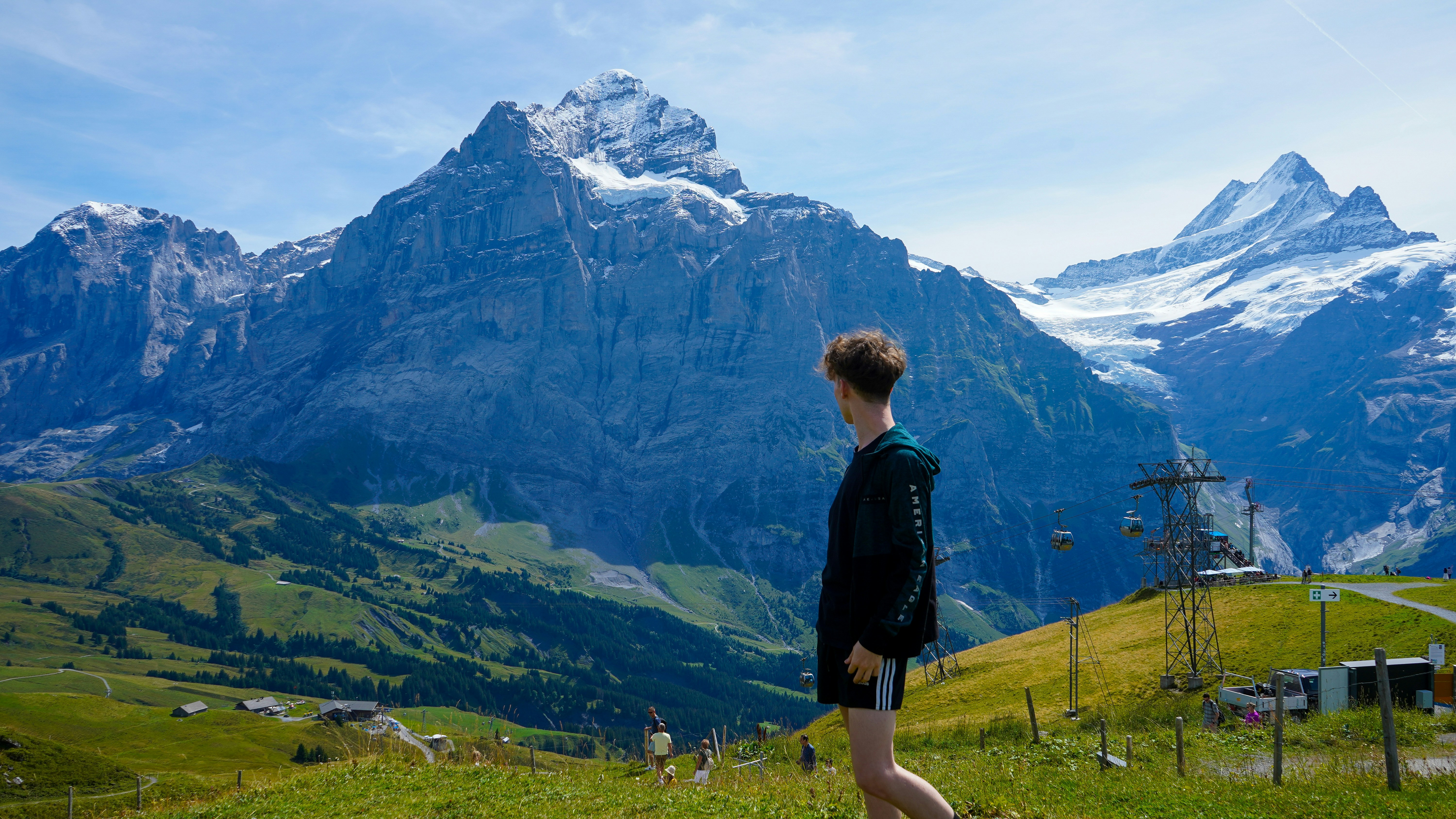 A man standing on top of a lush green hillside