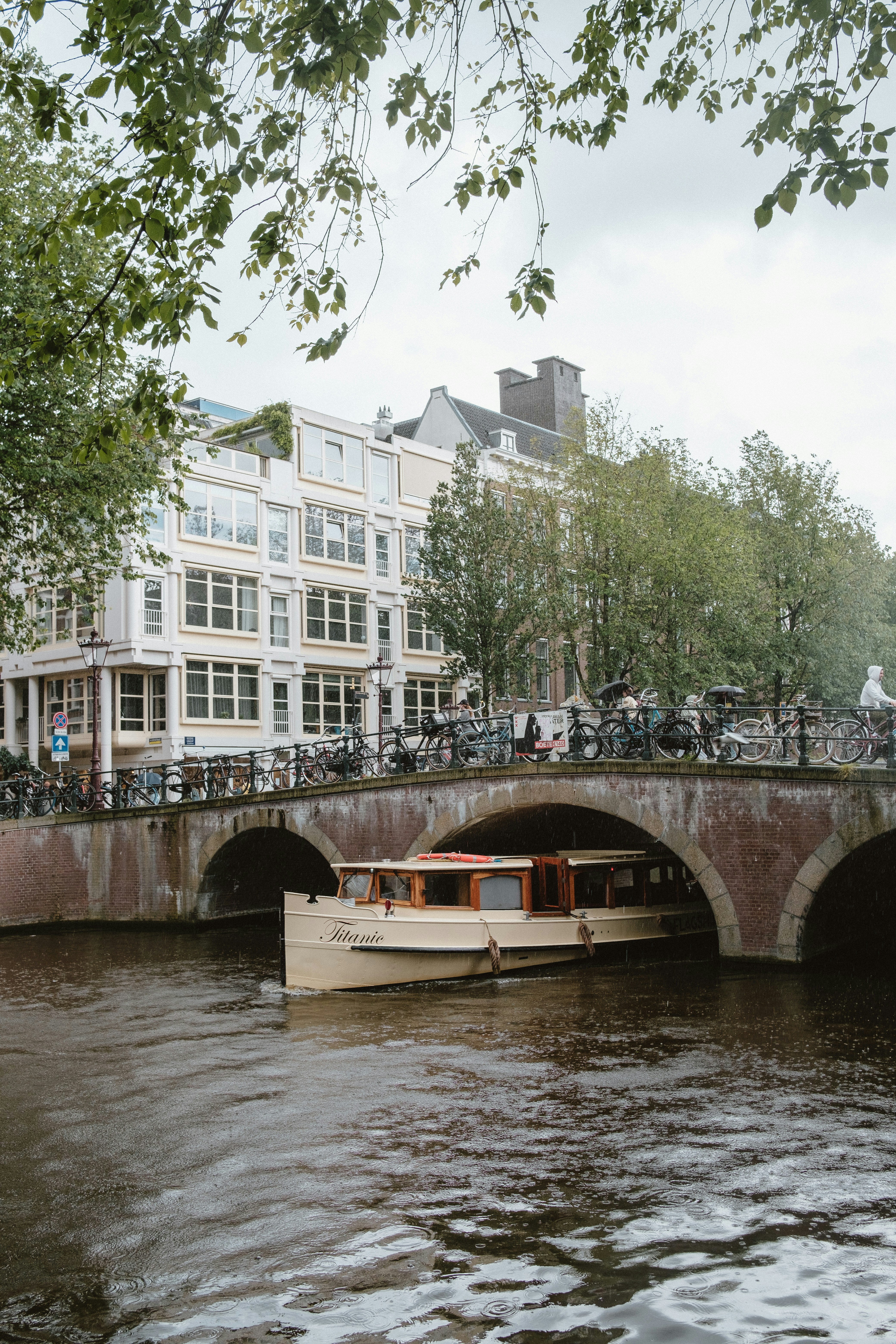 A boat traveling down a river under a bridge