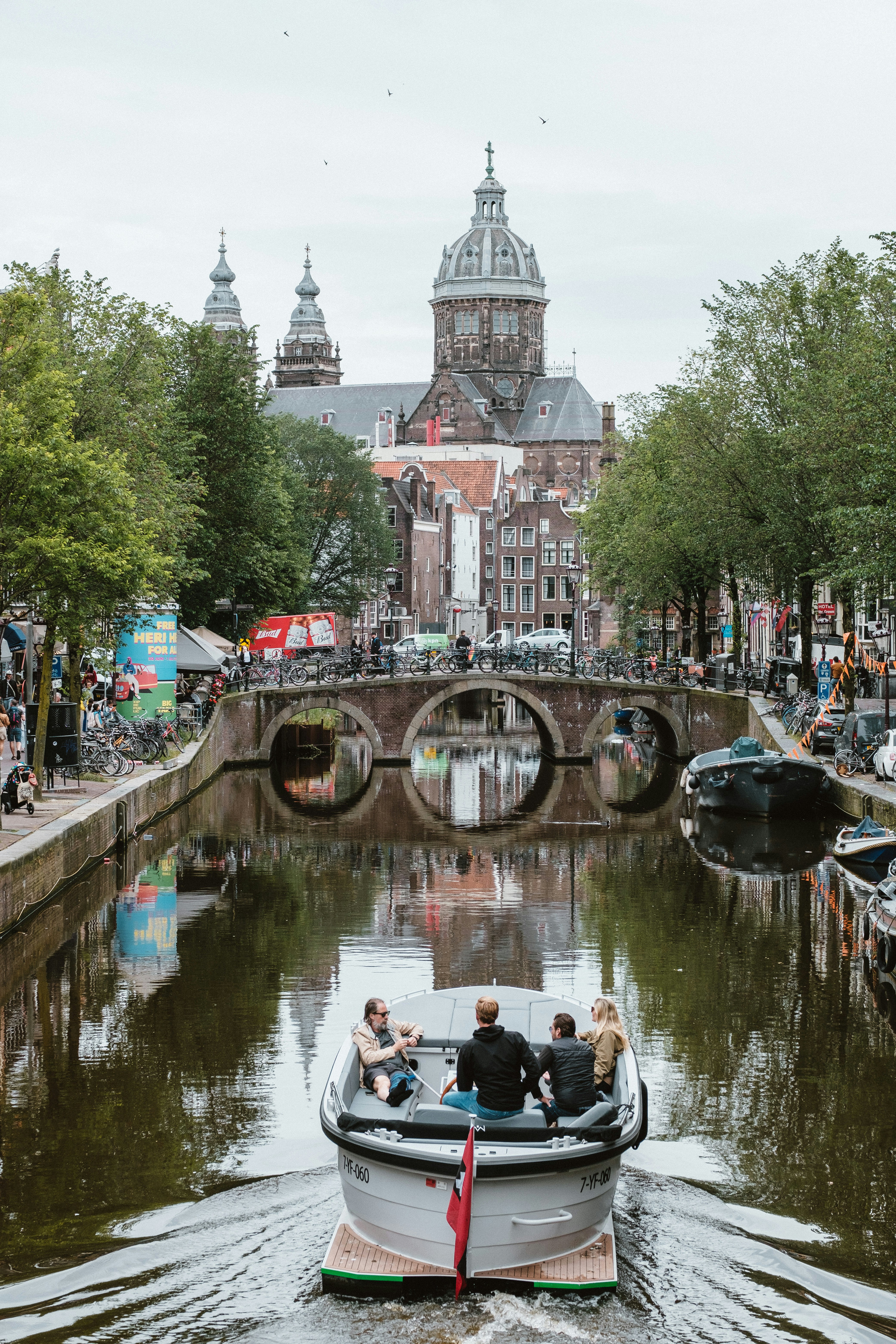 A boat traveling down a river next to a bridge