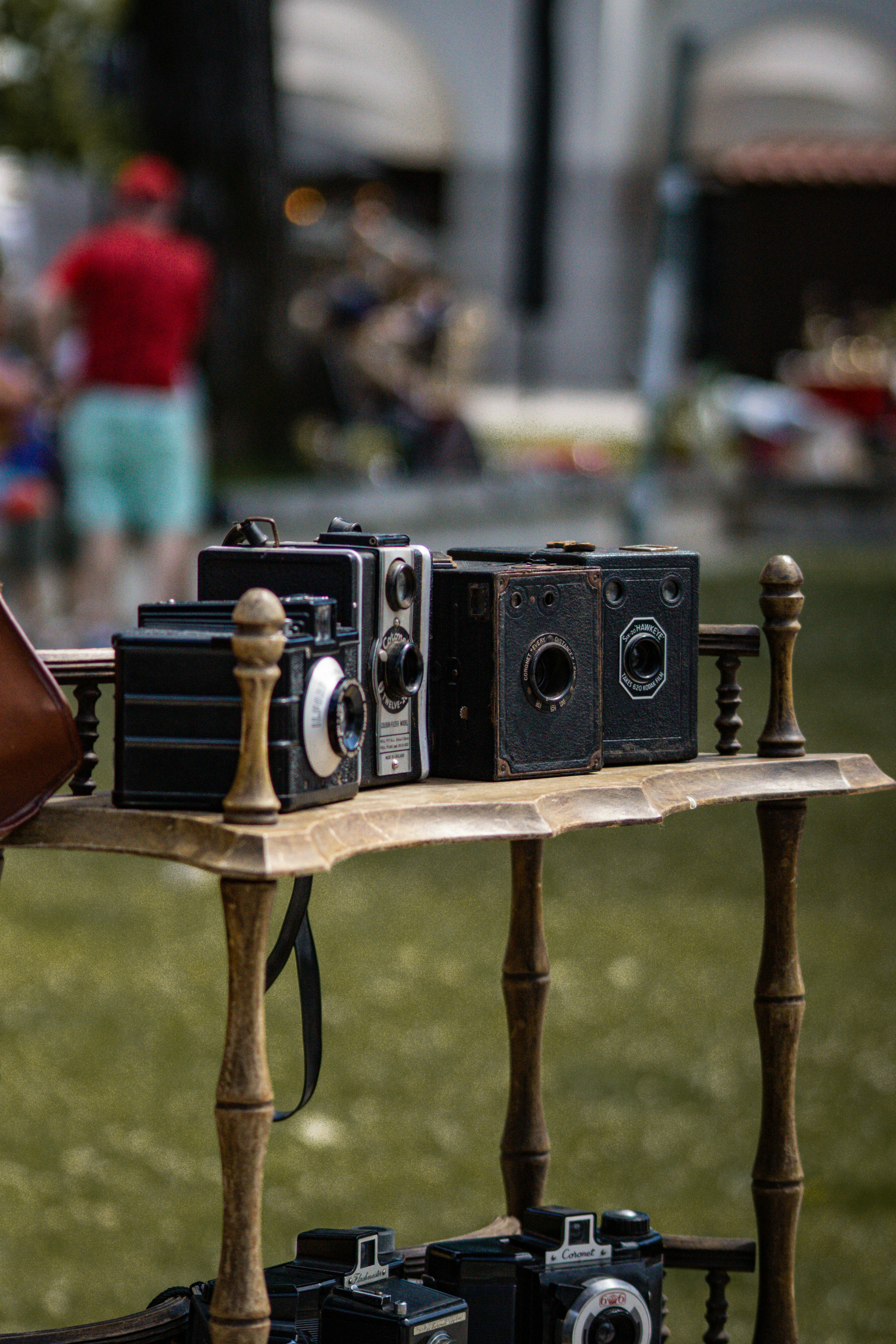 A wooden table topped with lots of old cameras