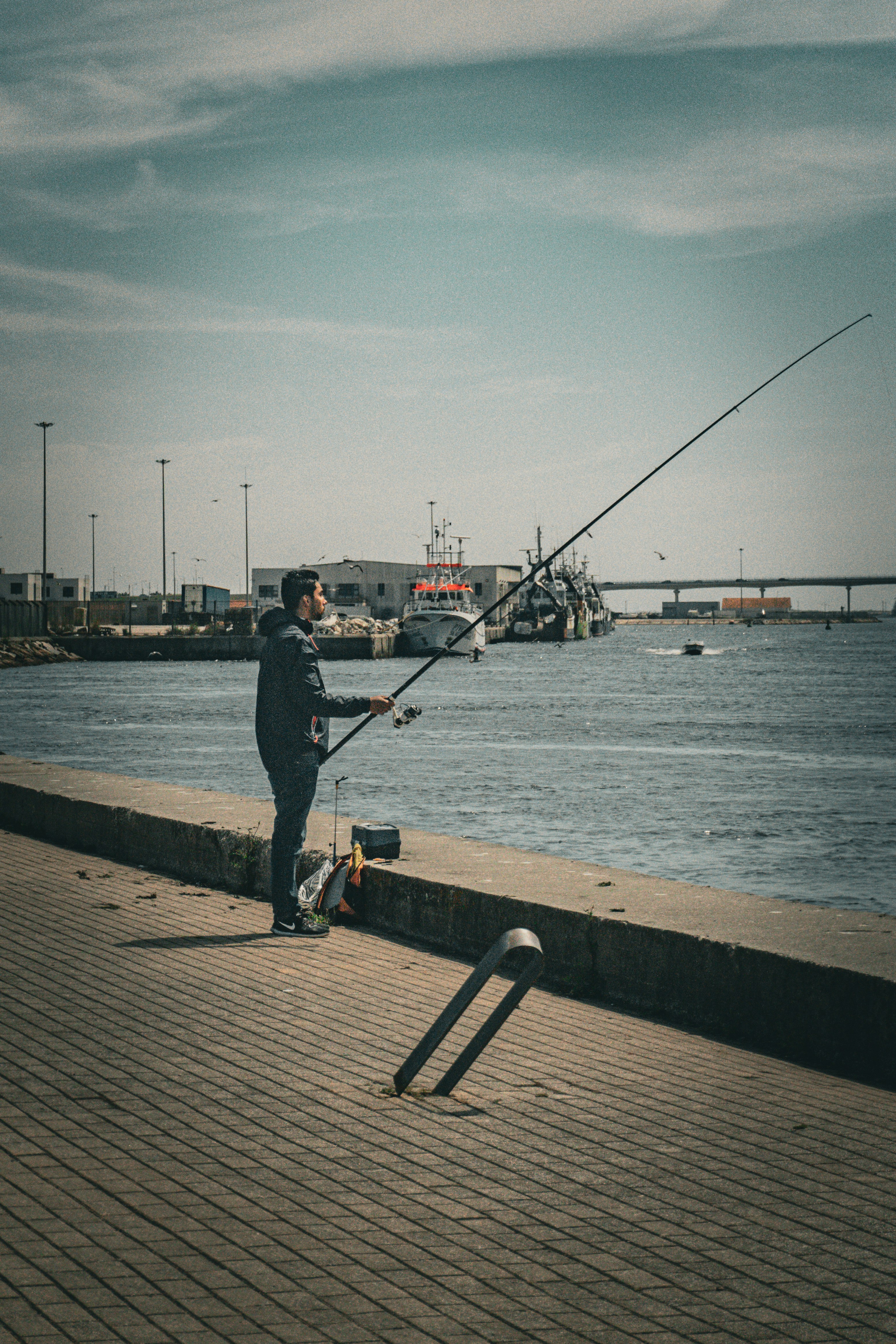 A man standing on a pier holding a fishing pole