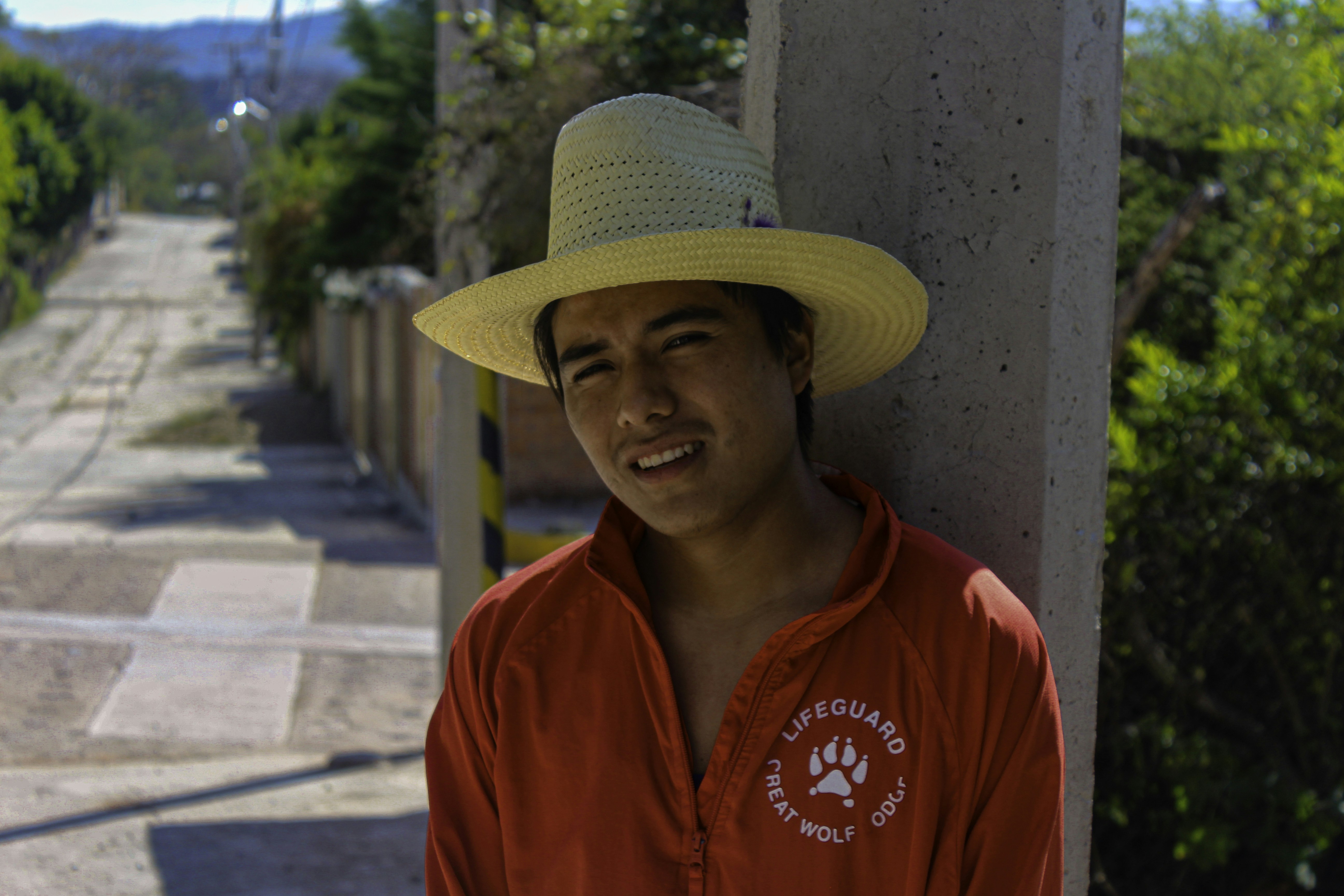 Fotomural A man wearing a hat leaning against a wall