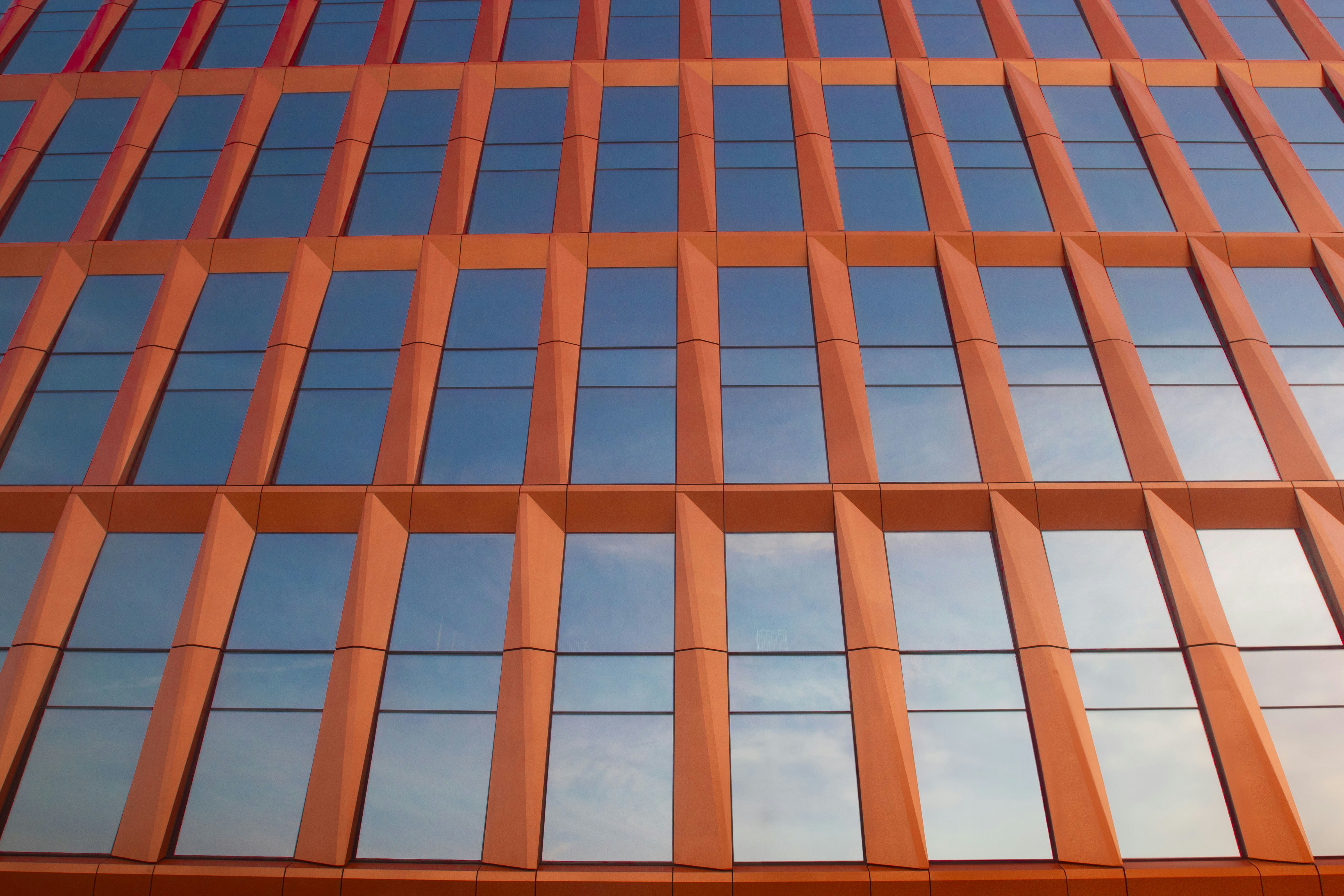 A tall building with lots of windows reflecting the sky