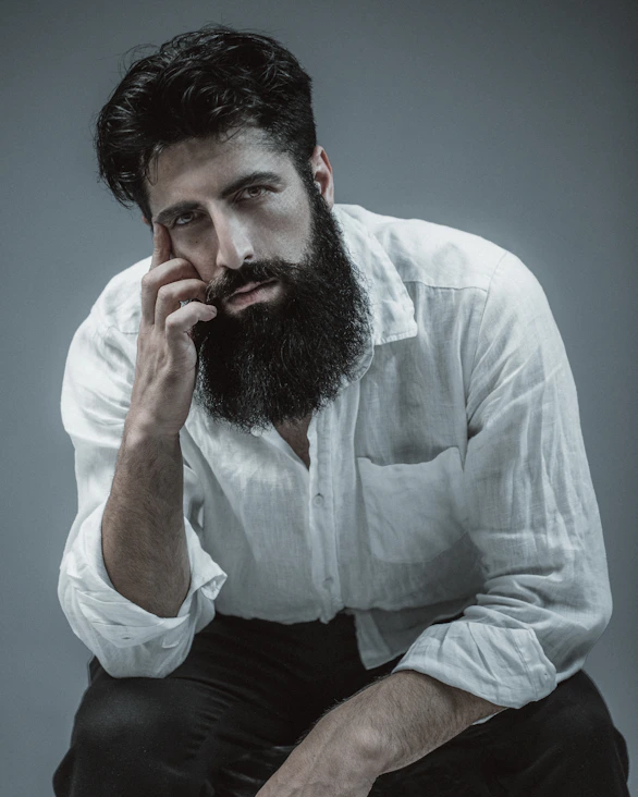 A man with a long beard sitting on a stool