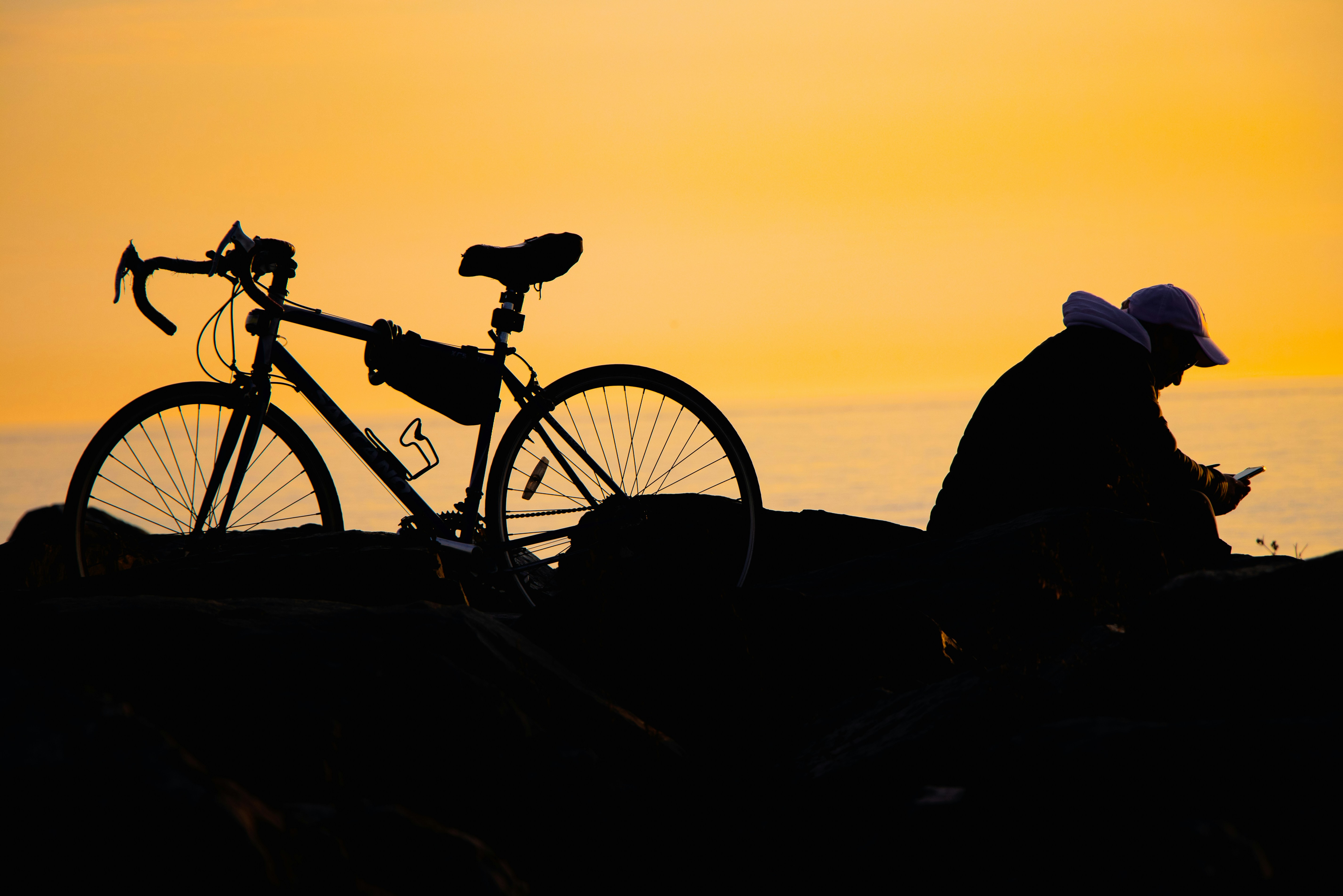 A man sitting next to a bike on top of a hill