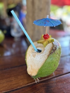 A coconut with a straw and an umbrella on top of it