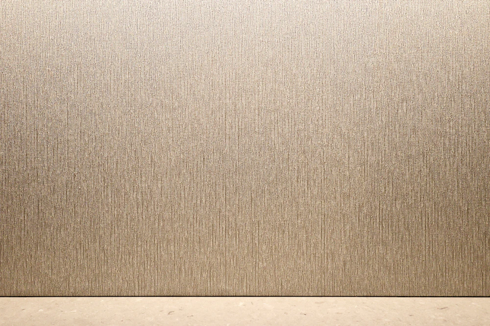 Parede com papel texturado em tom castanho-claro e soalho de madeira
