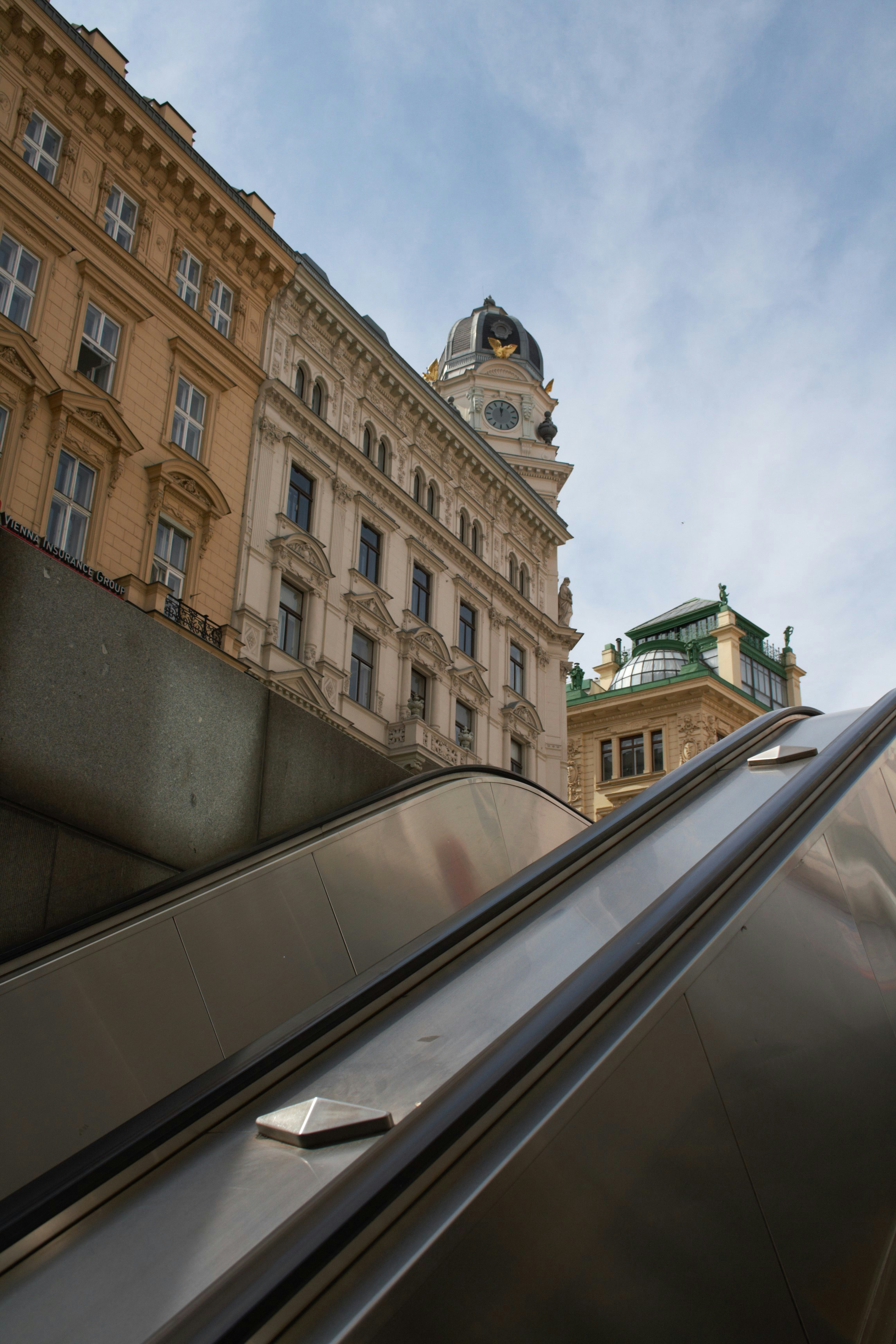 Una scala mobile di fronte a un edificio con una torre dell'orologio