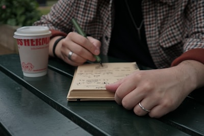A person sitting at a table writing on a notebook