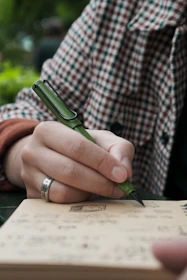 A person writing on a book with a pen