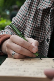 A person writing on a book with a pen