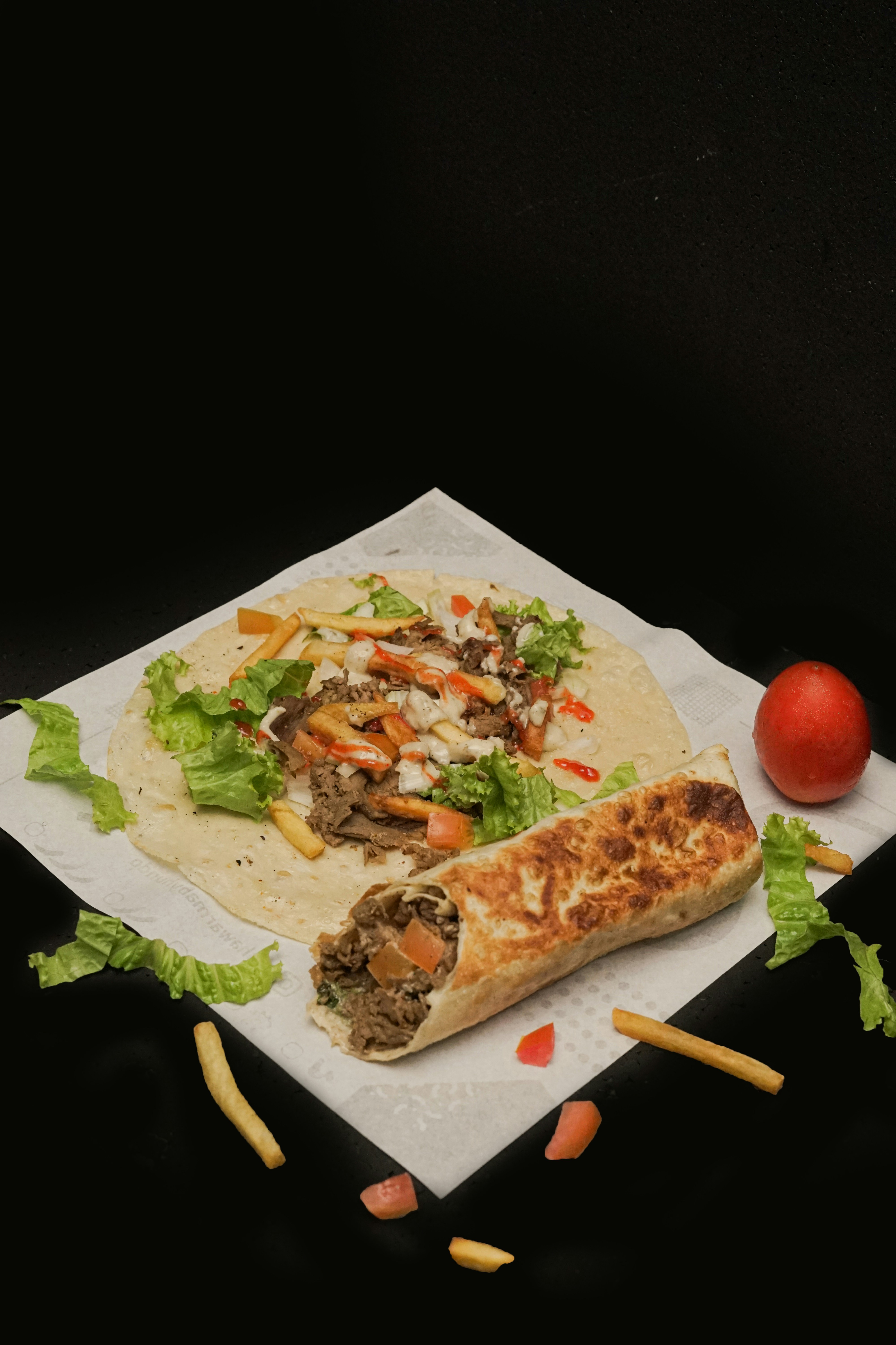 A taco with meat, lettuce, and tomatoes on it