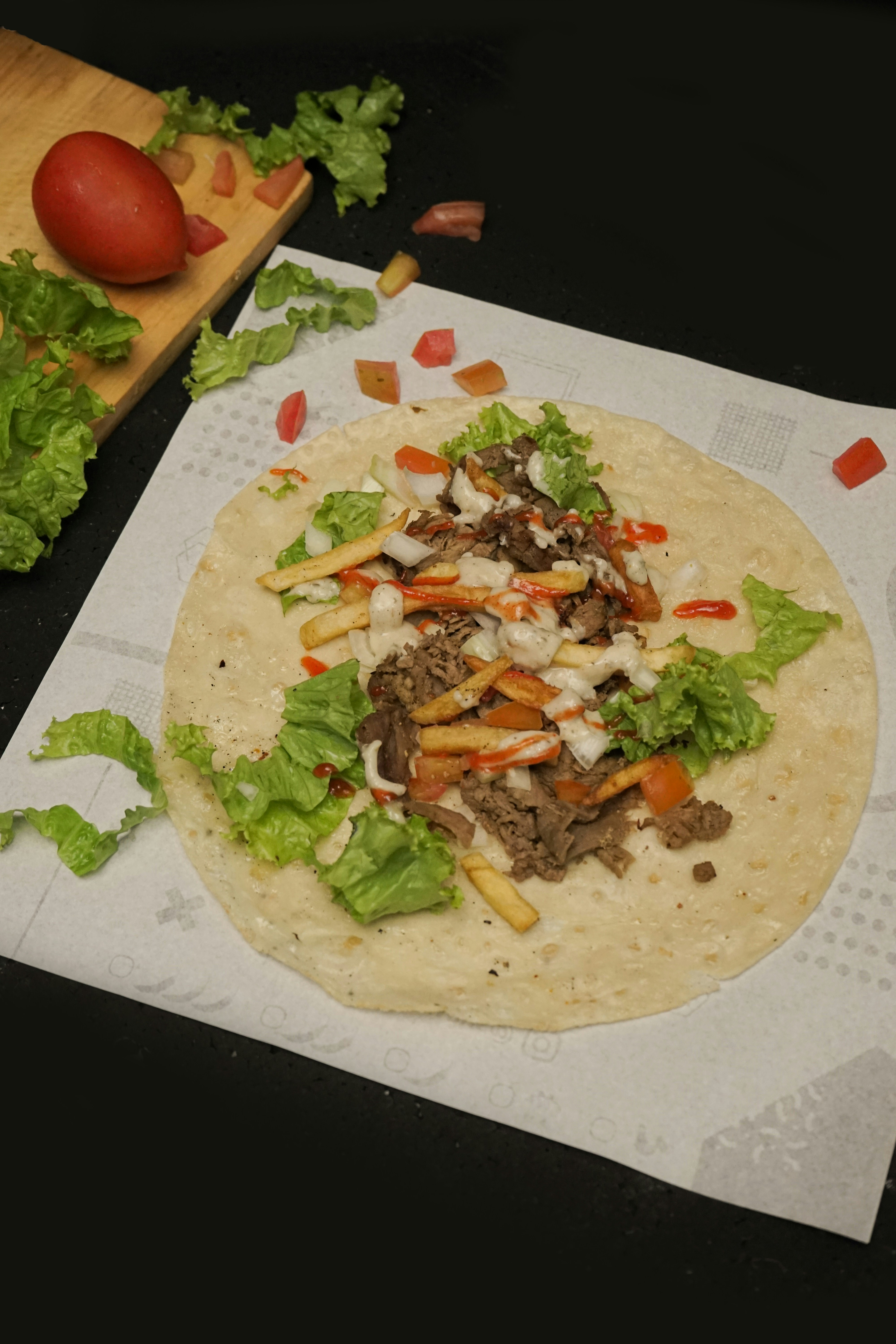 A tortilla with meat, lettuce and tomatoes