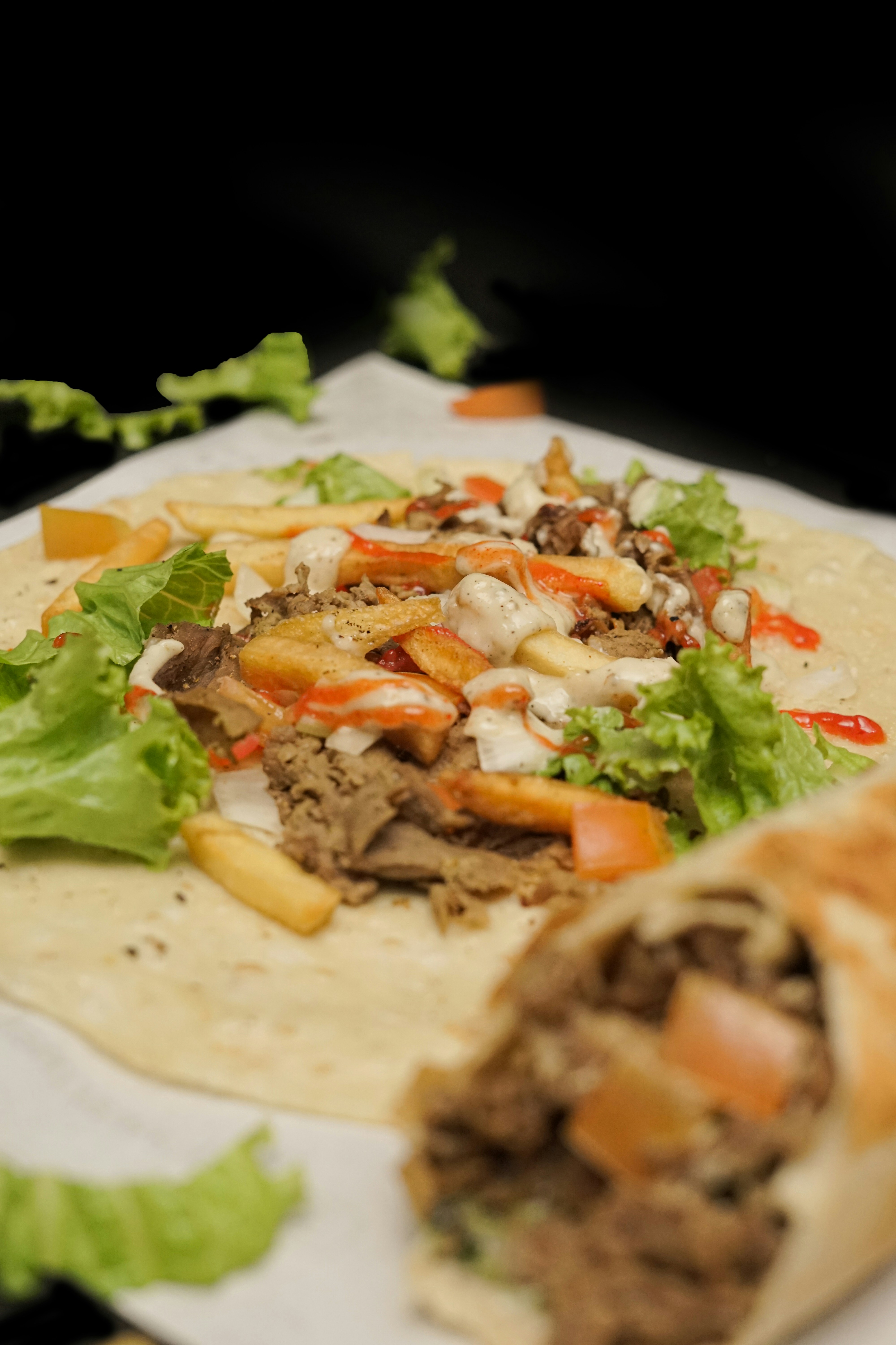 A tortilla filled with meat, cheese and lettuce