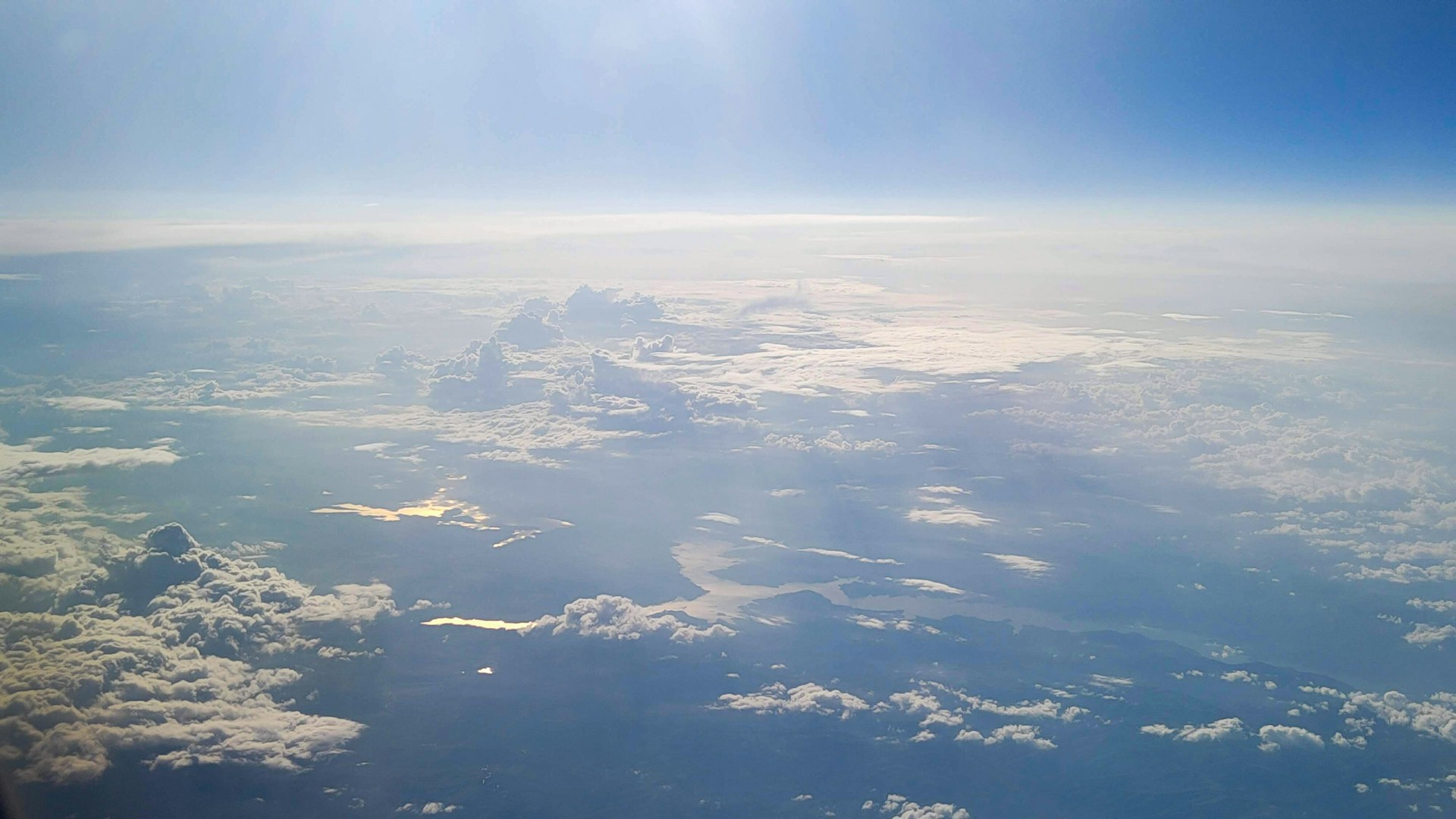 The sun is shining over the clouds in the sky