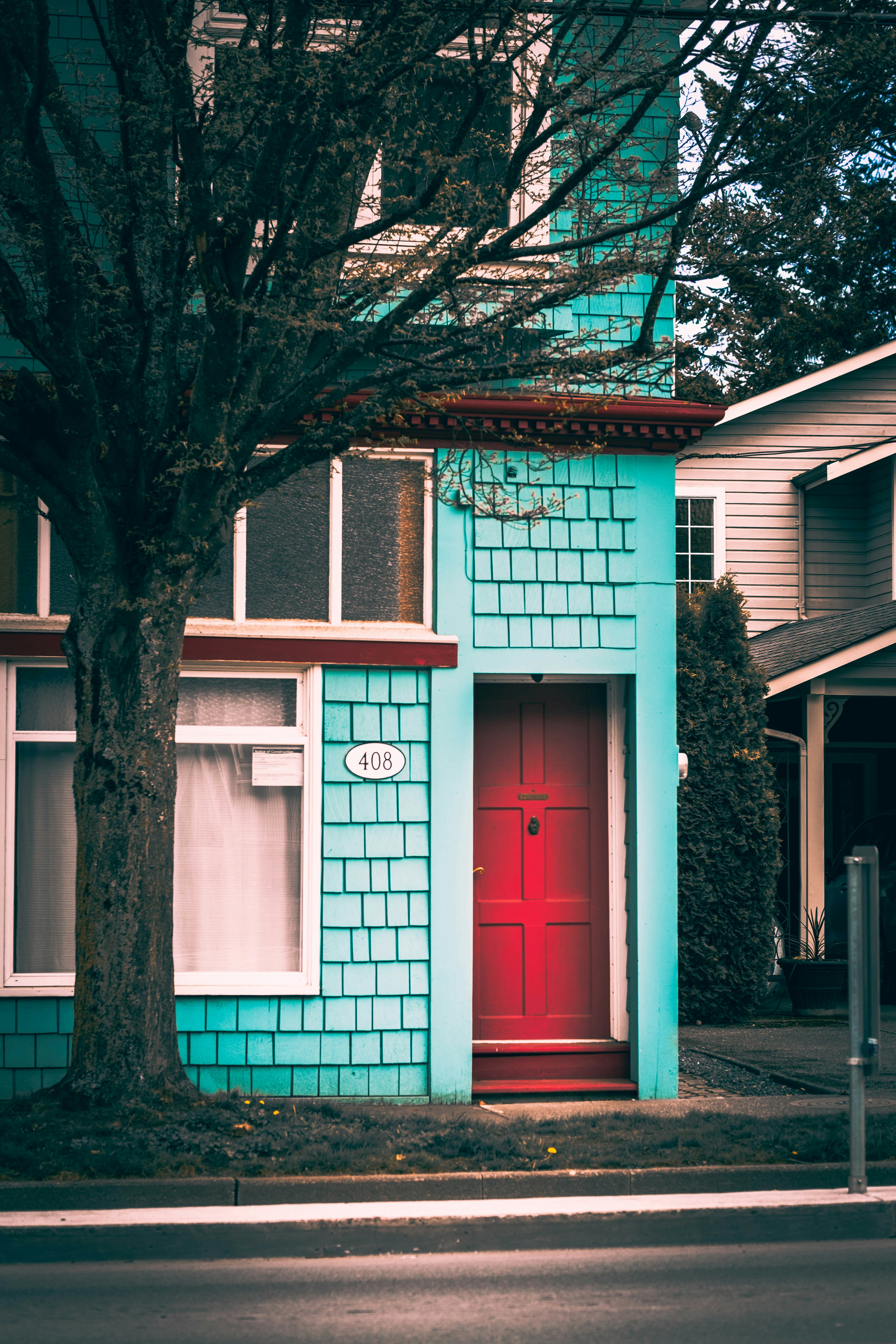 A blue house with a red door on a street corner