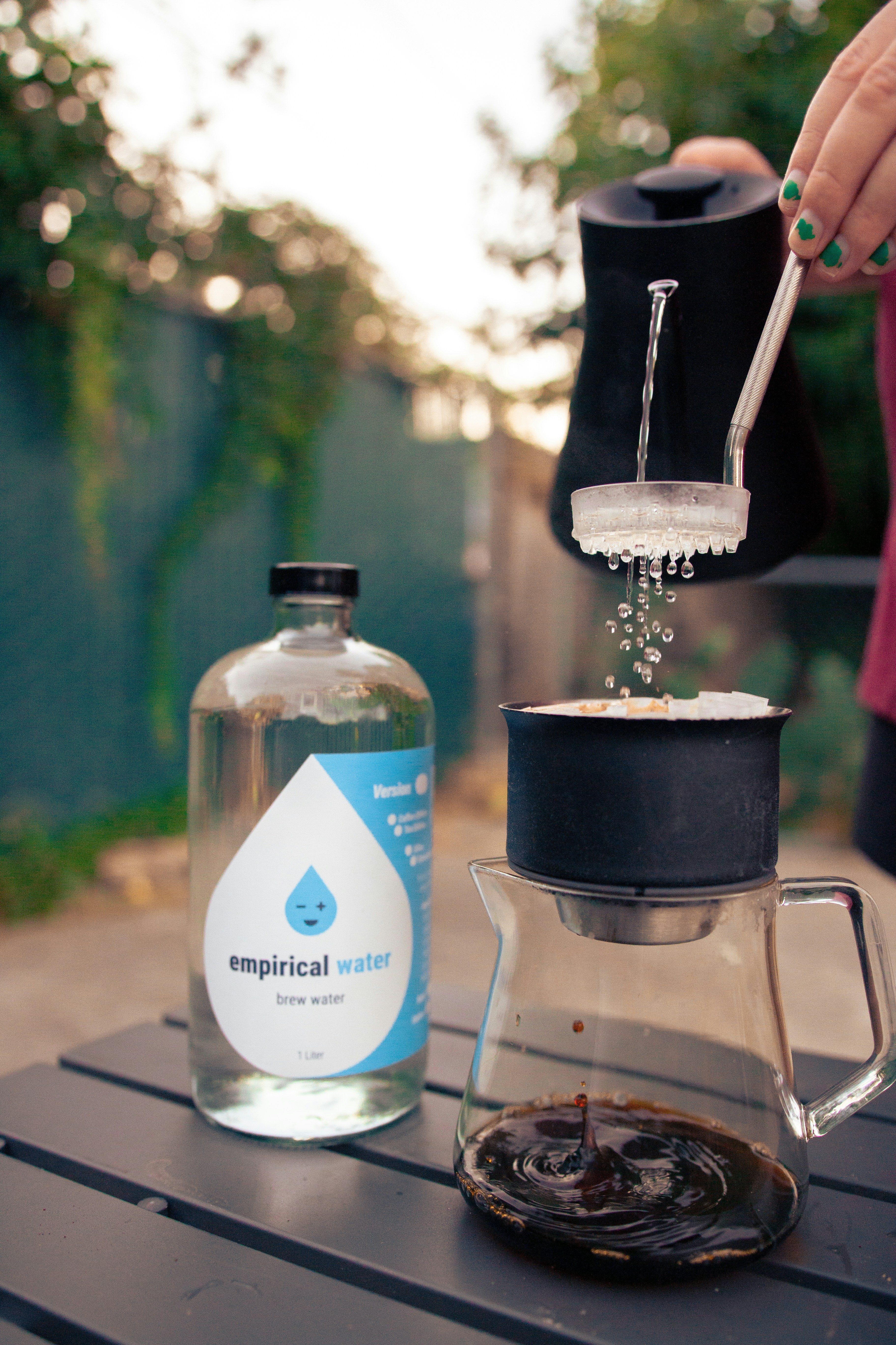 A person pours coffee into a glass cup