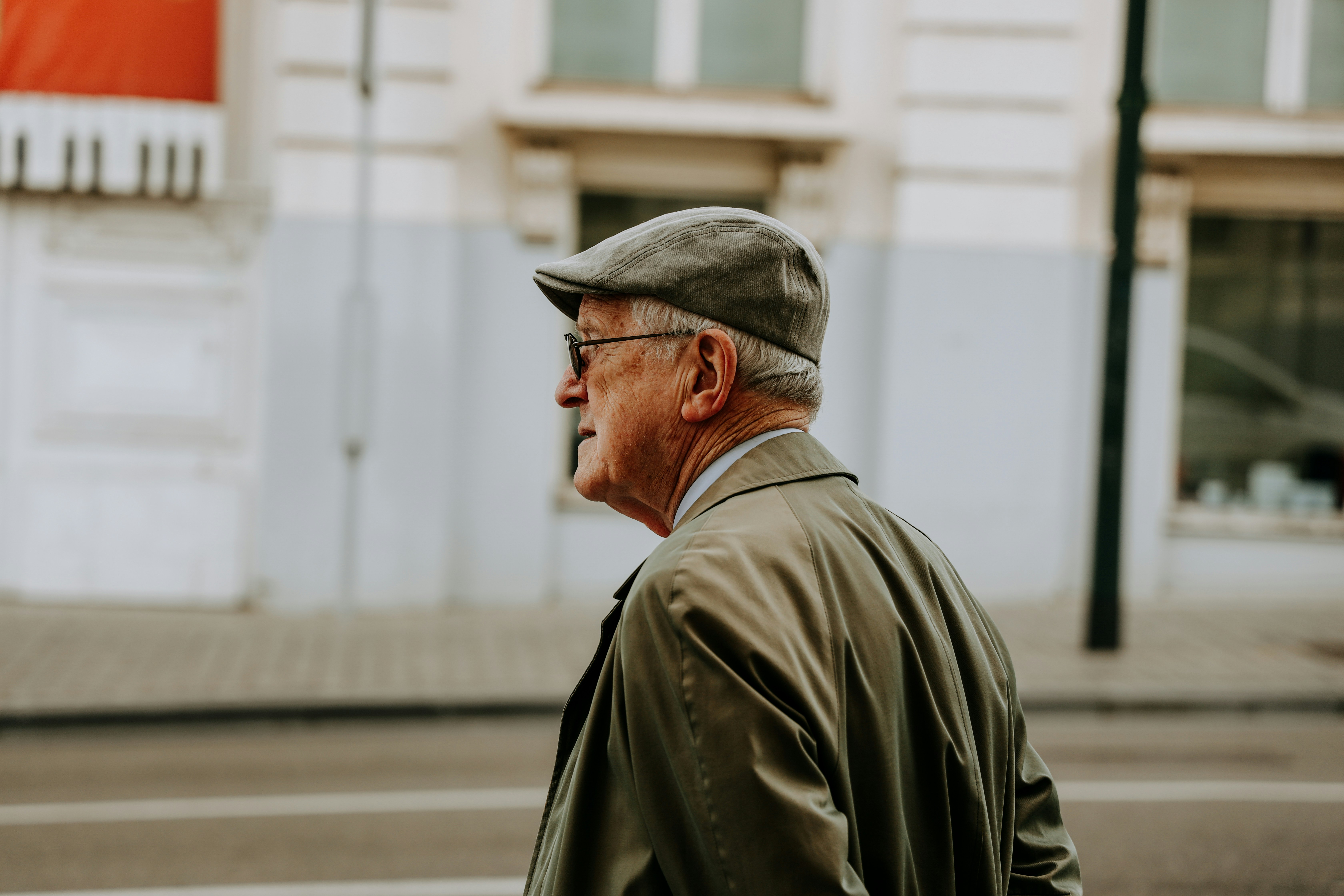 A close-up shot of an older man with a worried expression, looking into the distance, perhaps with a map or newspaper in the background. His face reflects deep concern and helplessness.