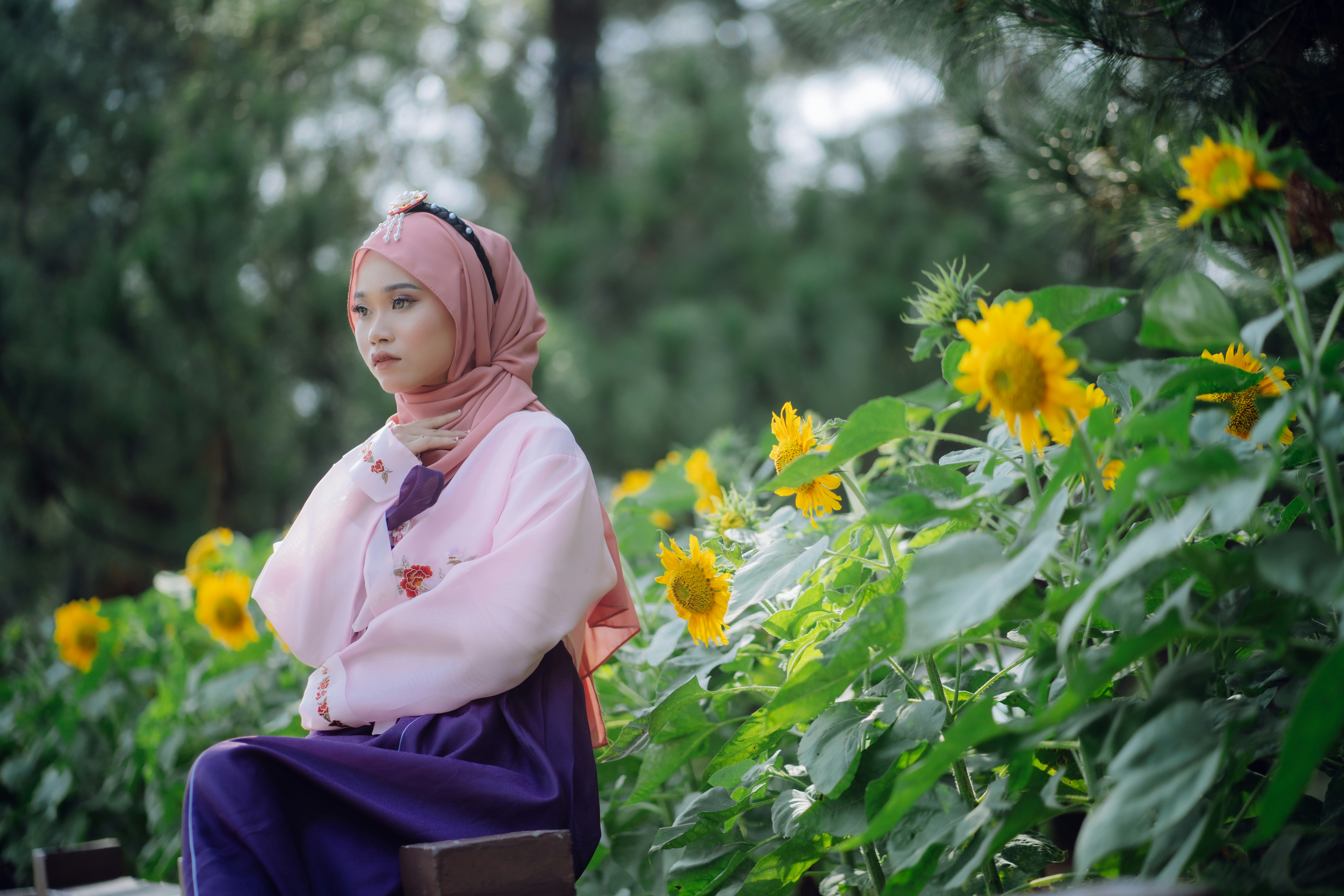 A woman sitting on a bench in front of flowers