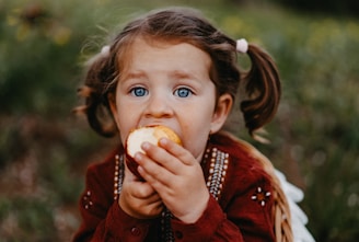 A little girl eating an apple in a field
