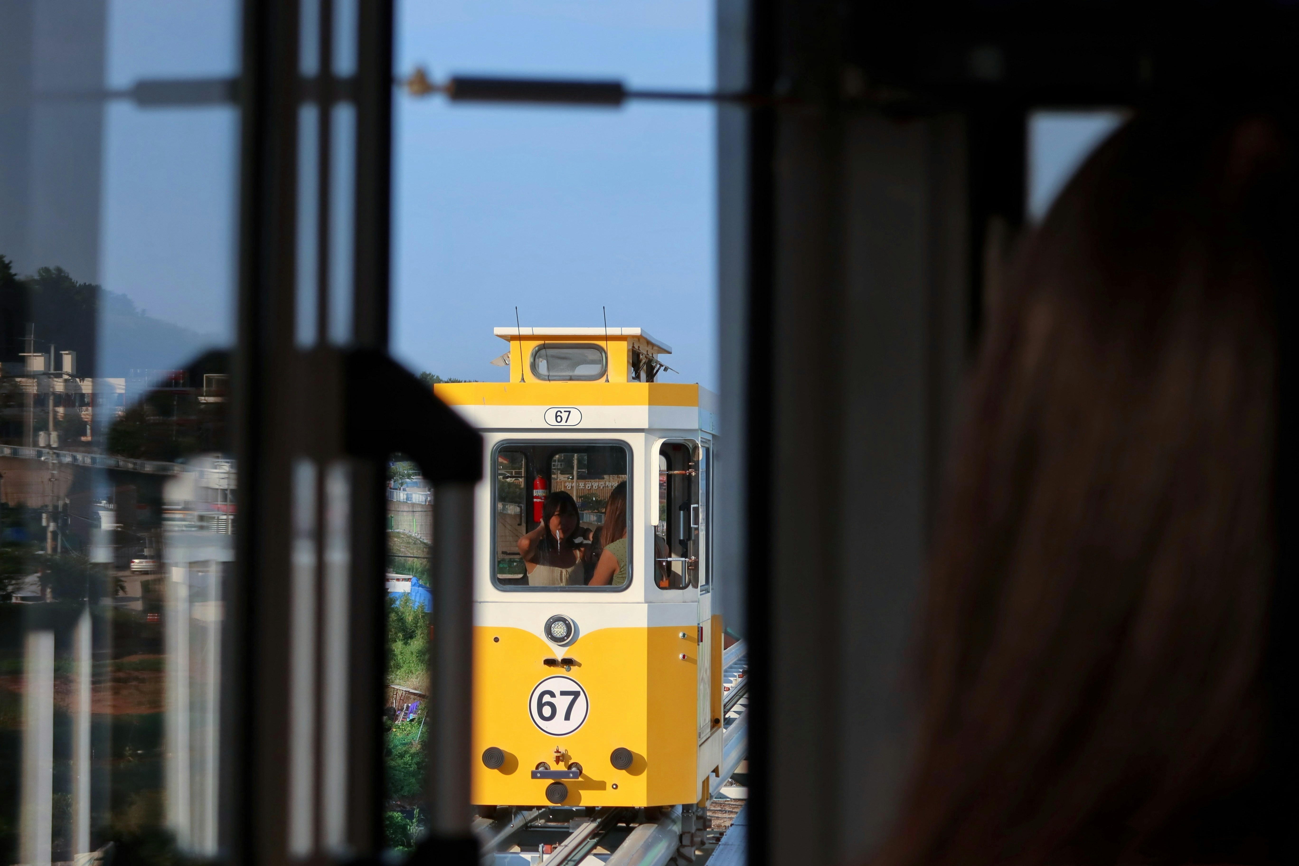 A yellow train traveling down train tracks next to a tall building