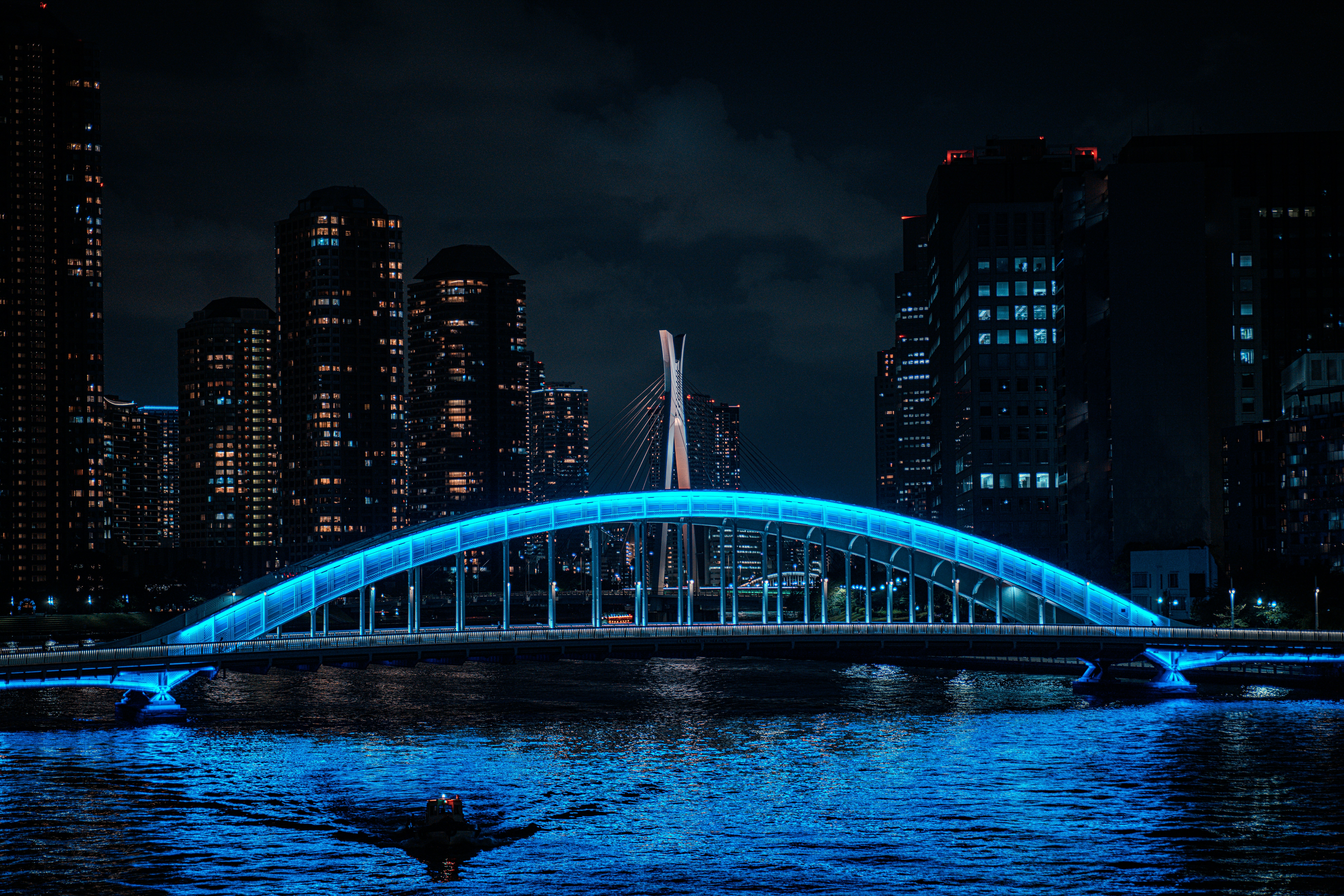 A blue lit bridge over a body of water