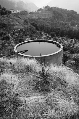 A large water tank sitting on top of a dry grass field