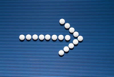Pills are arranged in the shape of a cross on a blue background
