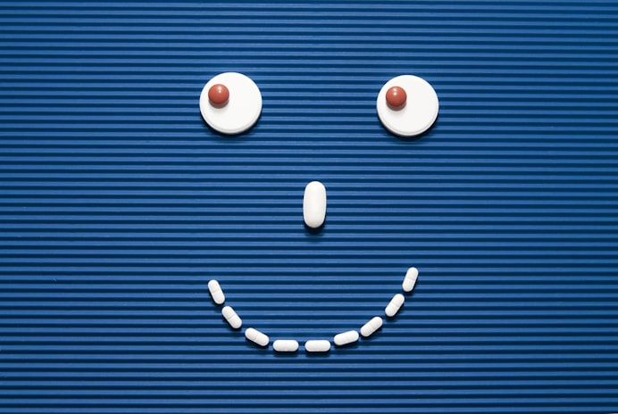 A smiley face made out of pills on a blue background